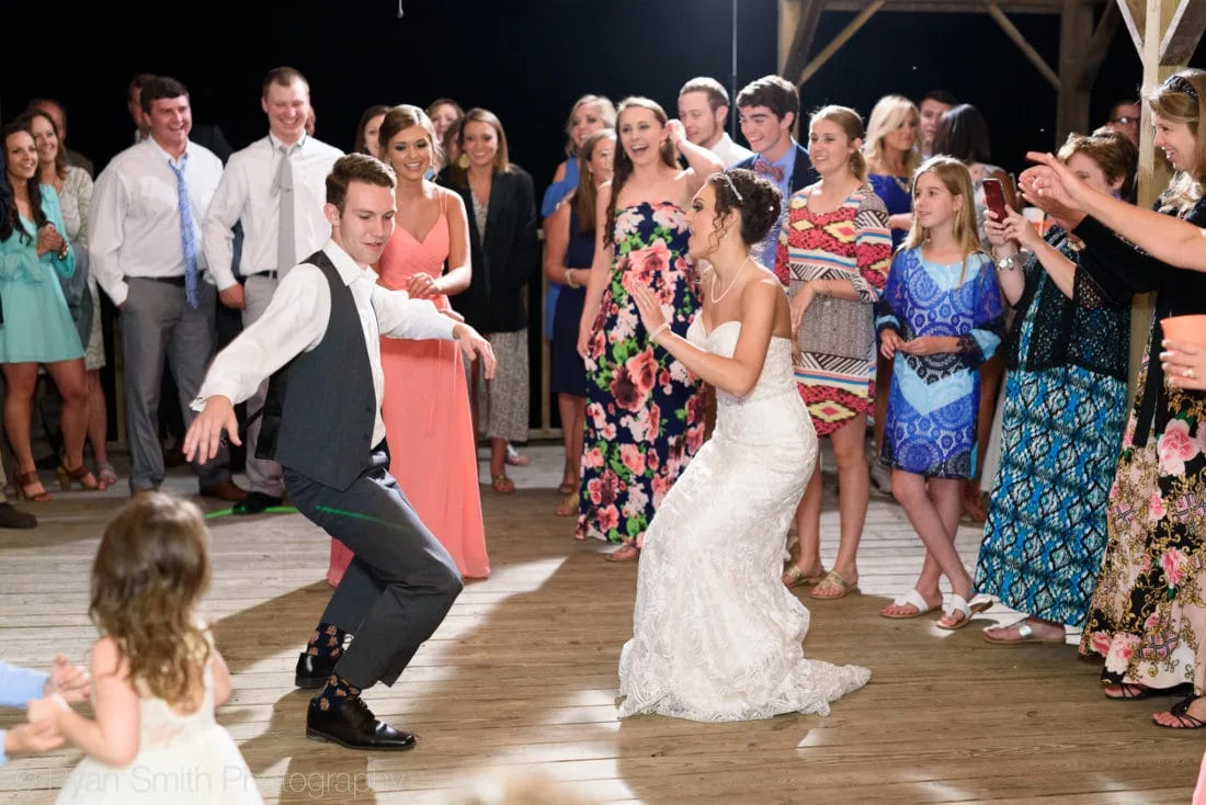 Groomsman shows off his dance moves next to the bride on the dock at Upper Mill Plantation