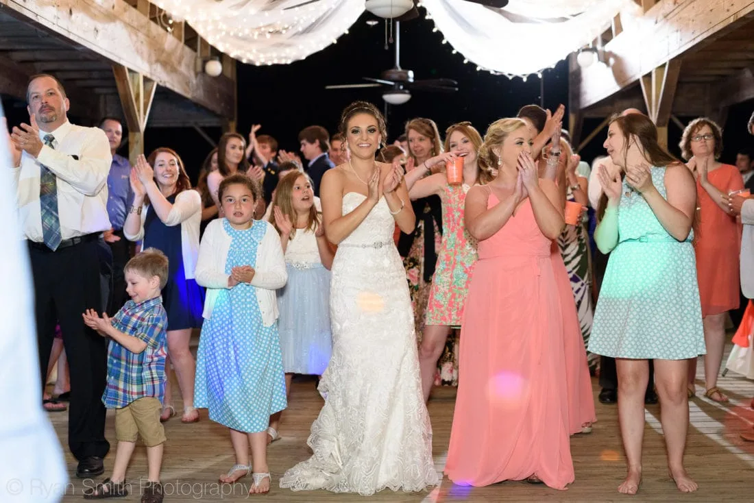 Bride claps and dances with guests on the dock at night at Upper Mill Plantation