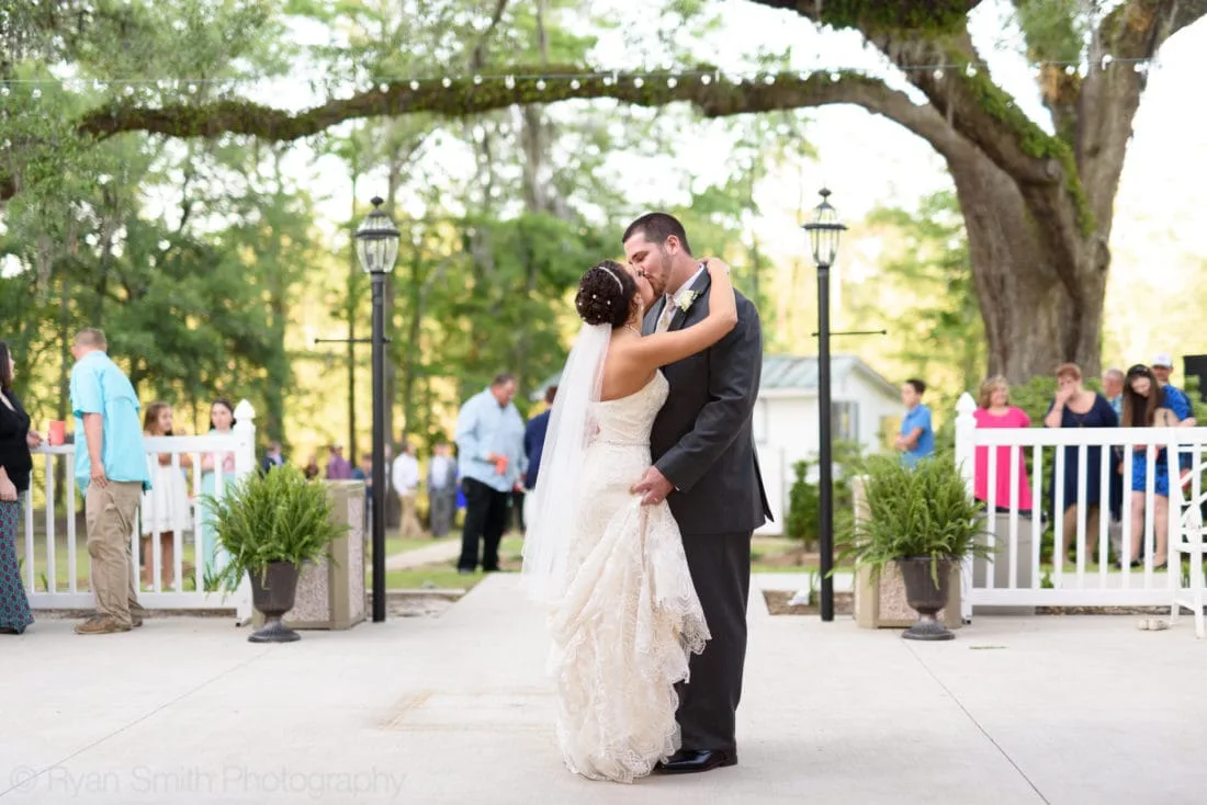 Bride and groom kiss under the oak tree during their first dance at Upper Mill Plantation