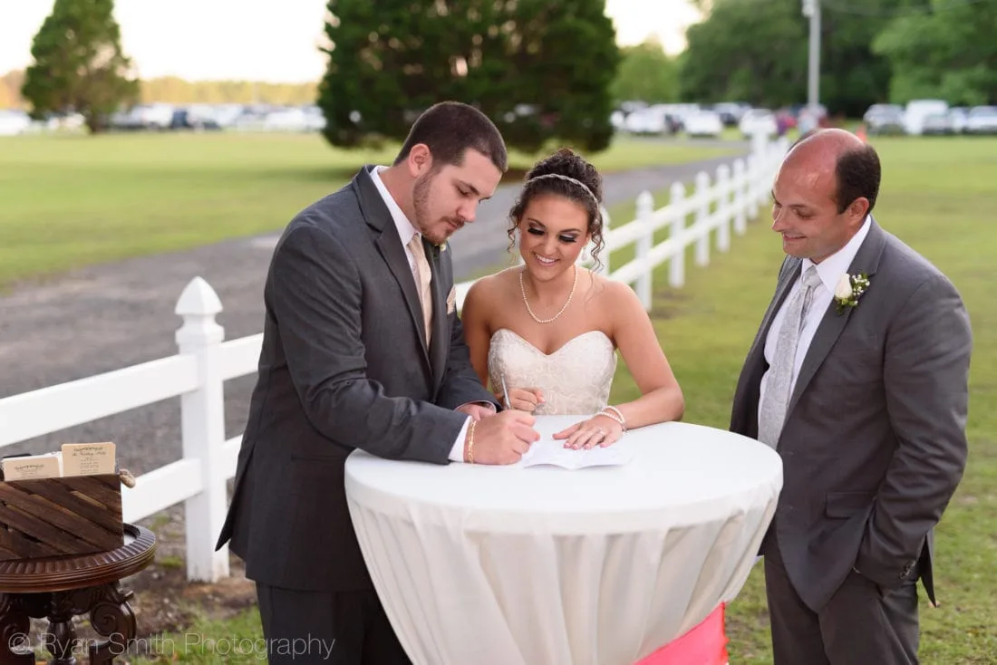 Bride and groom sign the marriage license at a cocktail table at Upper Mill Plantation