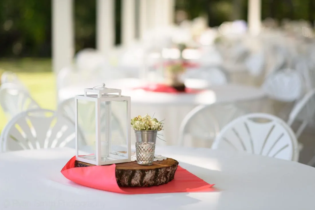 Lantern and mason jar centerpiece on a wood slice at the reception tables at Upper Mill Plantation