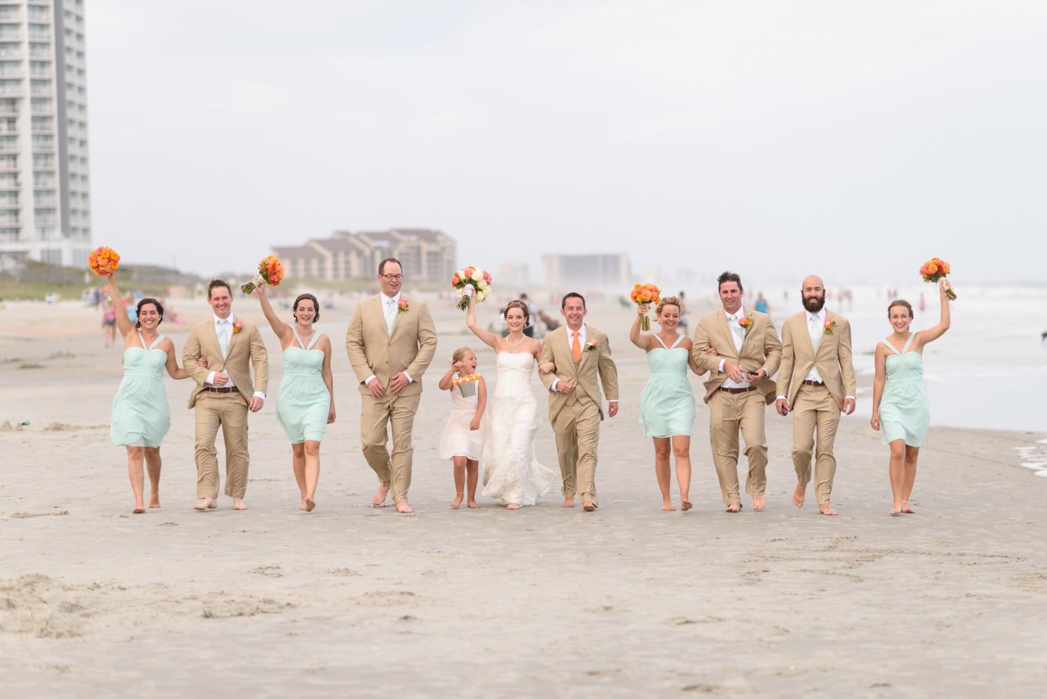 Wedding party walking together down a crowded beach - Hilton at Kingston Plantation