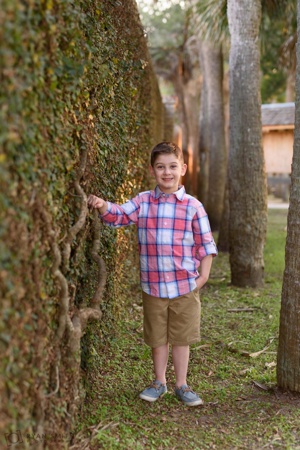 Boy leaning against the ivy wall of the castle Huntington Beach State Park