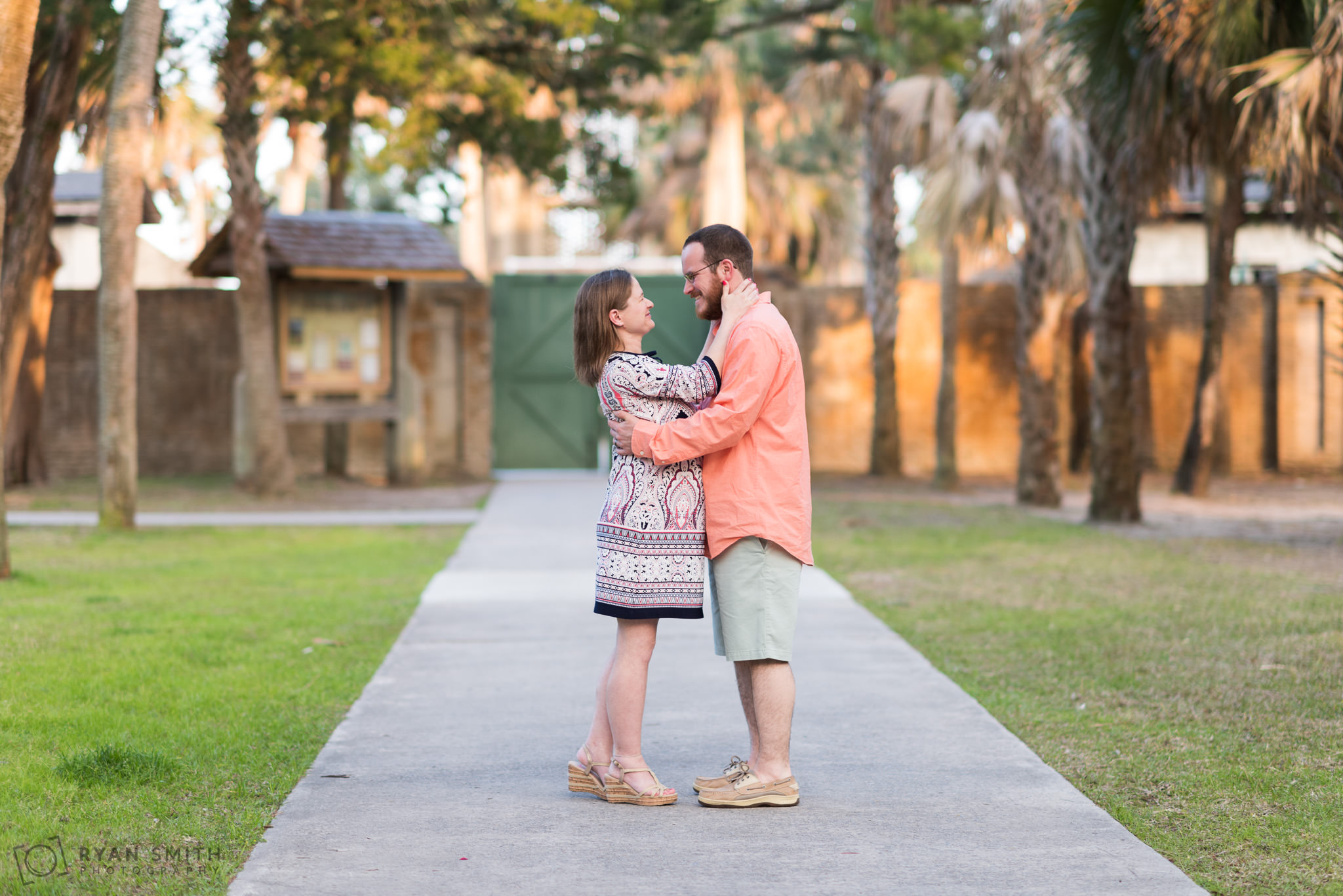 Maternity portrait of couple smiling at each other in front of the Atalaya Castle Huntington Beach State Park
