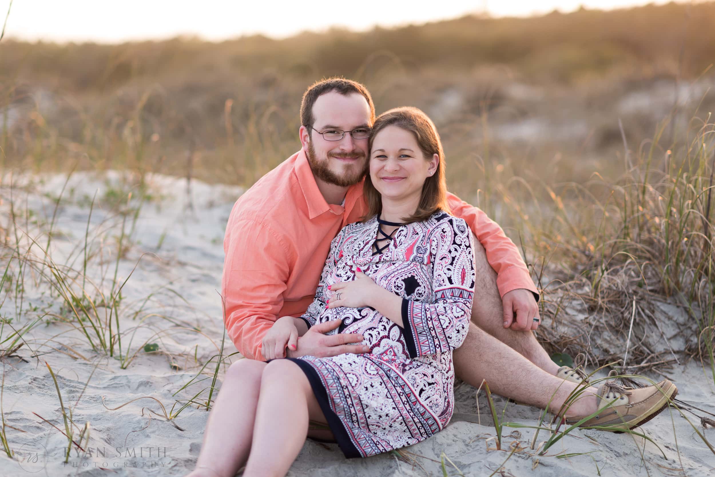 Maternity portraits of man and woman sitting by the dunes - Huntington Beach State Park