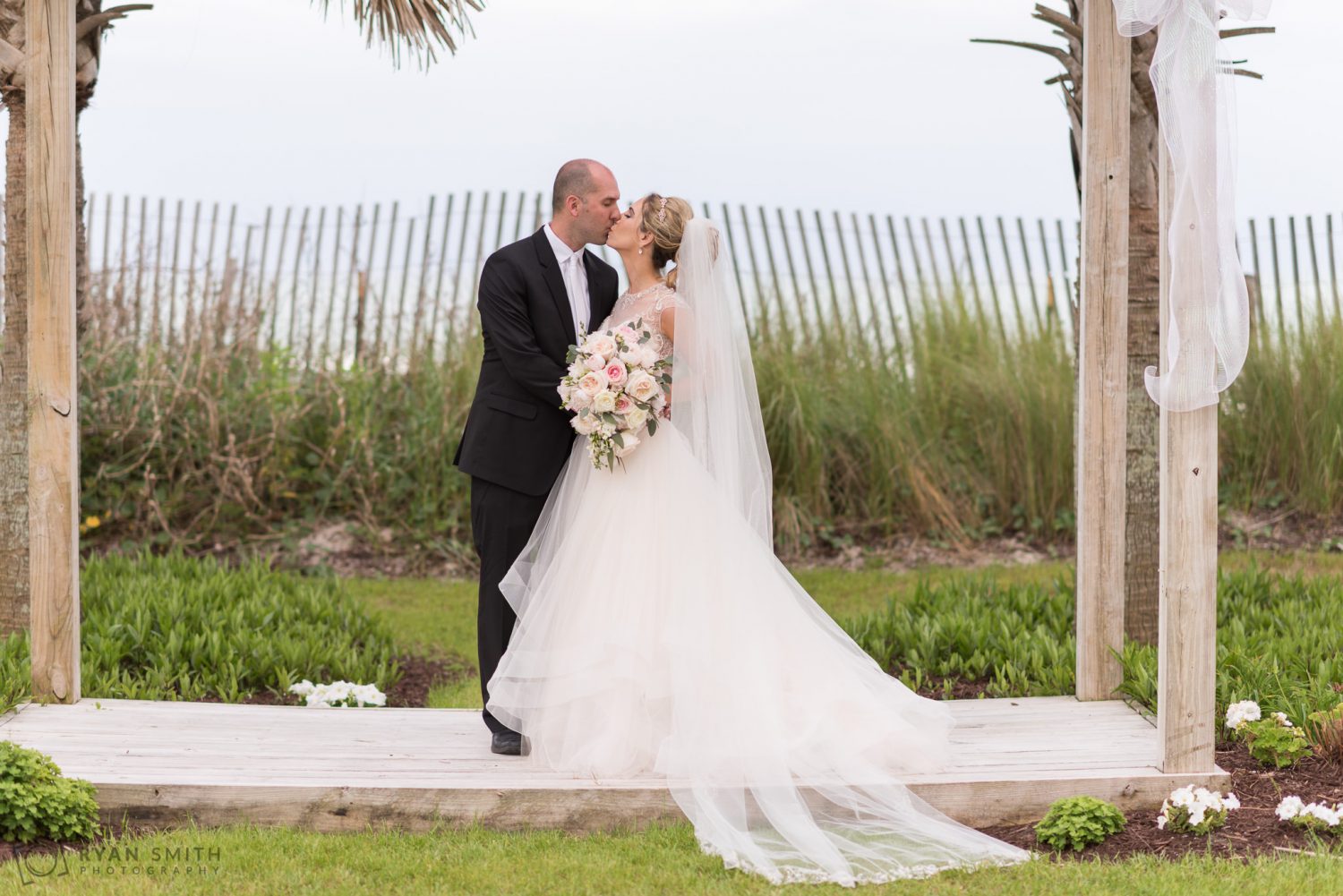 Bride and groom posing for a kiss after ceremony Hilton Myrtle Beach Resort
