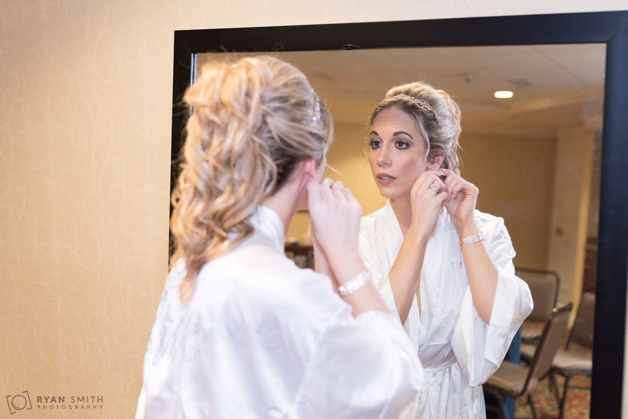 Bride putting on earrings in mirror Hilton Myrtle Beach Resort