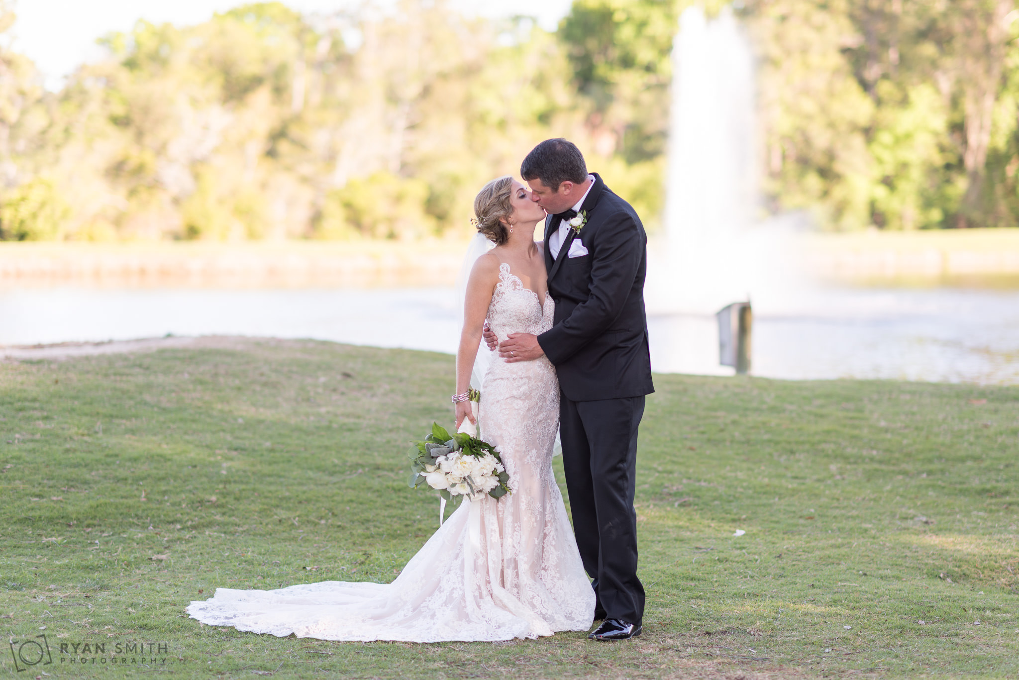 Bride and groom kissing in front of the lake Pawleys Plantation