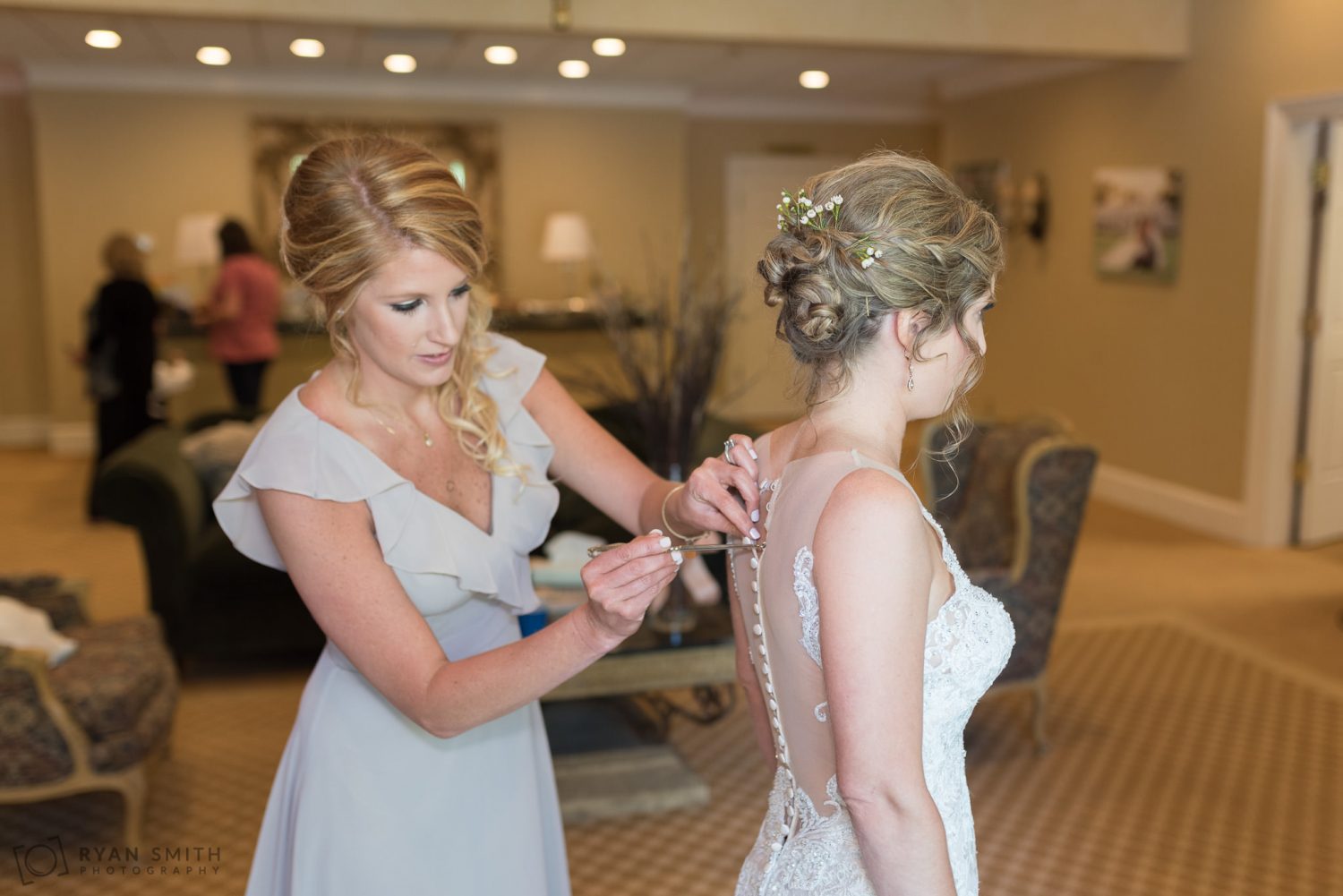 Bridesmaids helping bride button up her dress Pawleys Plantation