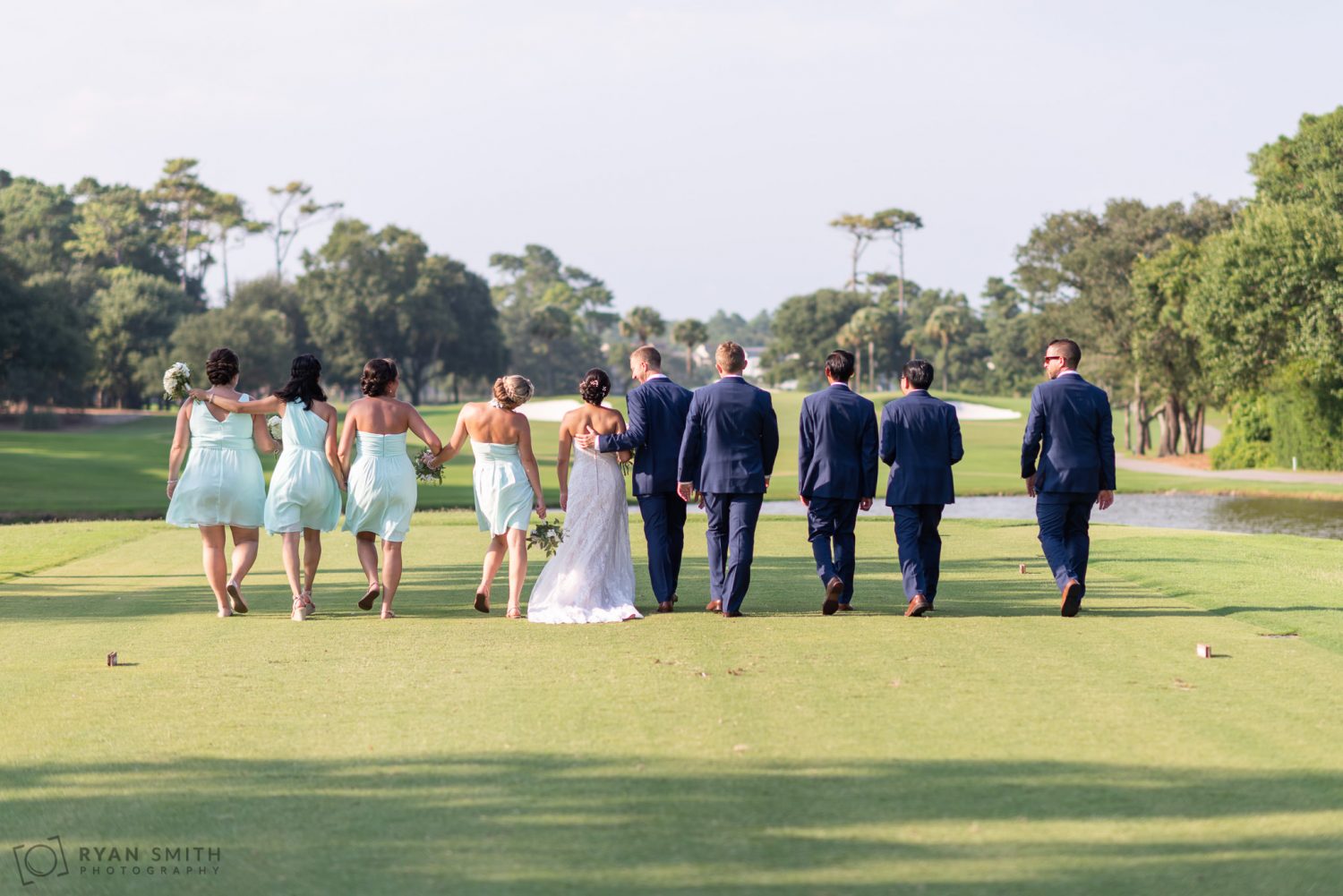 Bridal party walking down the golf course Dunes Golf and Beach Club