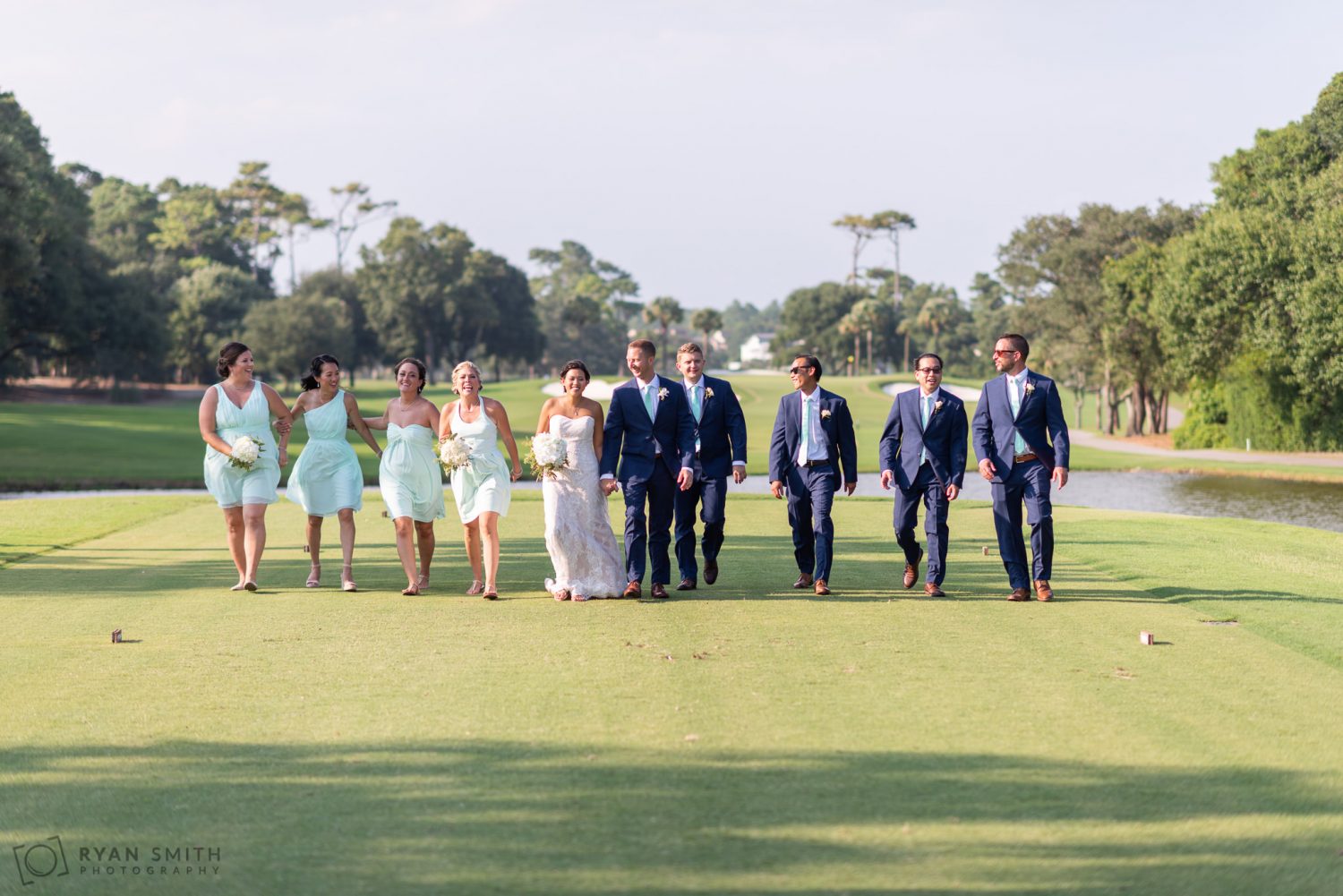 Bridal party walking down the golf course Dunes Golf and Beach Club