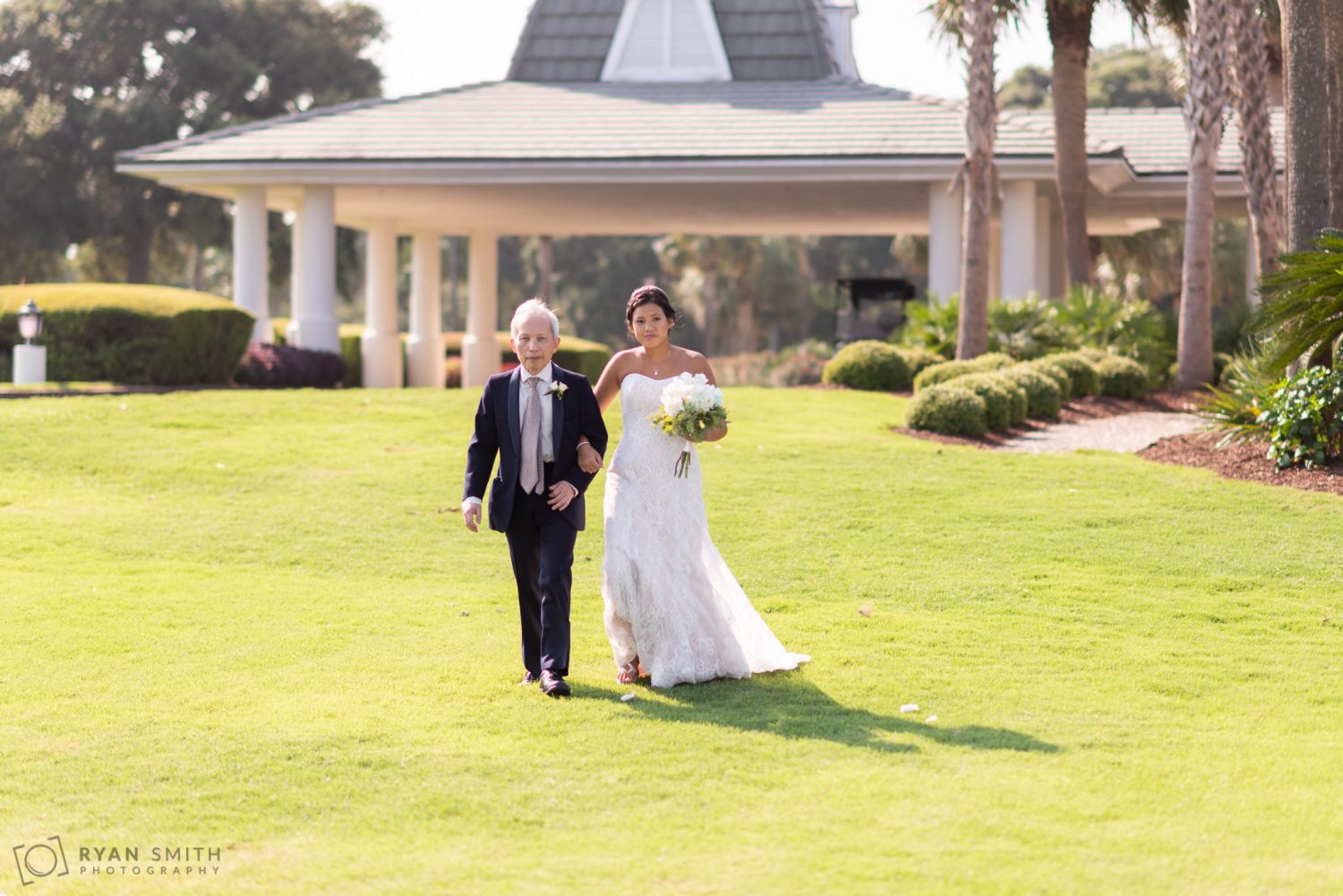 Bride and father walking towards the ceremony Dunes Golf and Beach Club