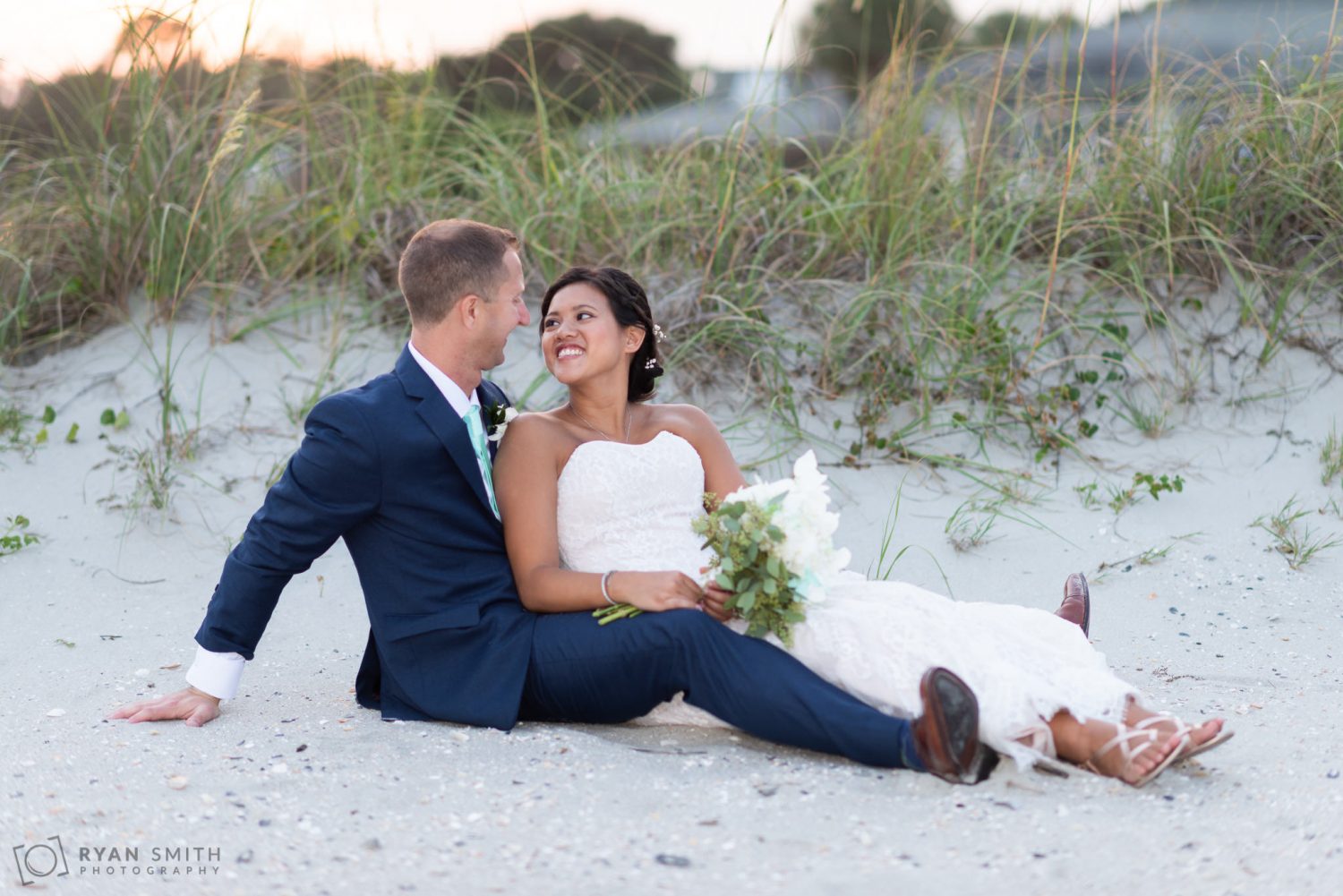 Bride and groom sitting in front of the dunes Dunes Golf and Beach Club