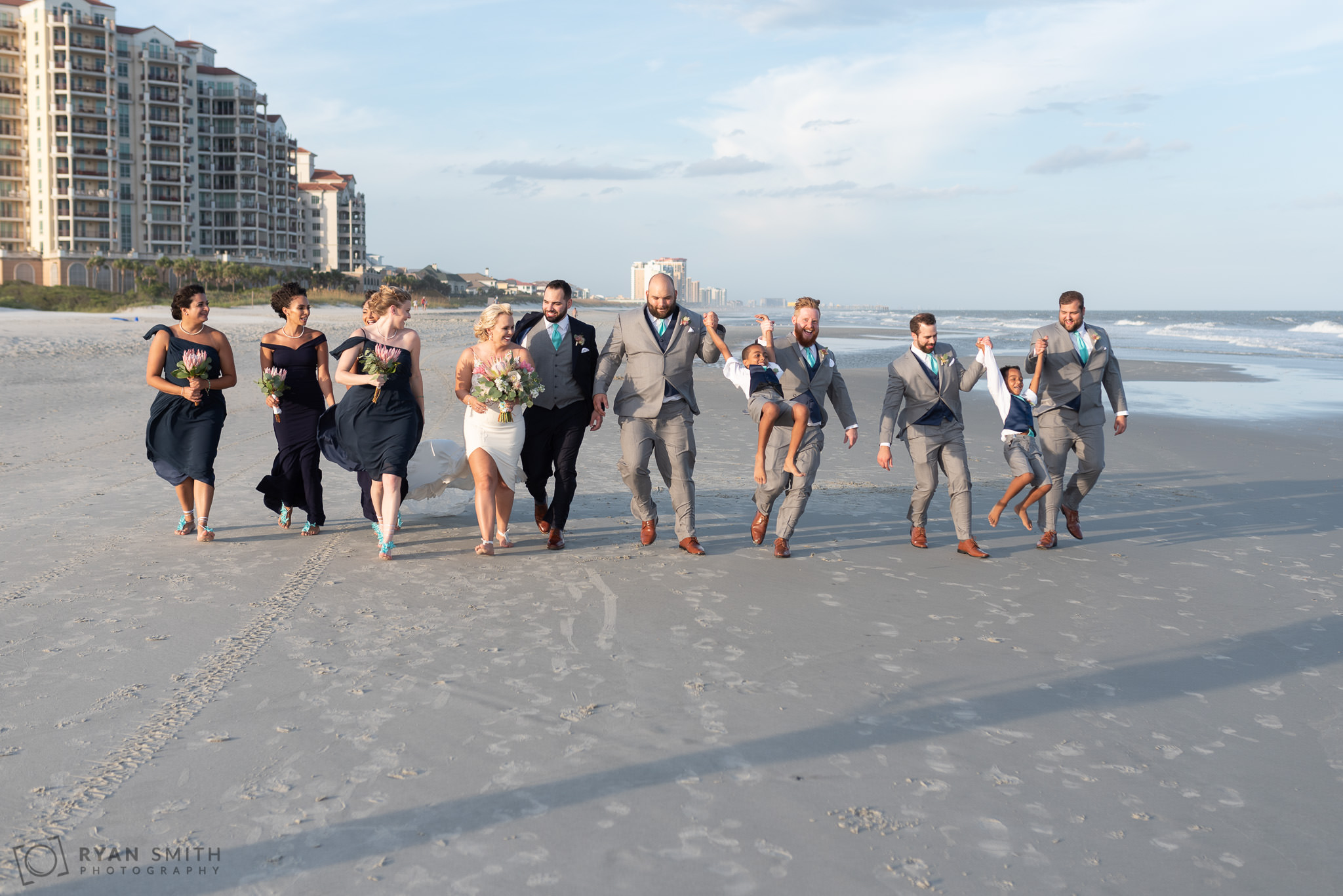 Bridal party having fun walking down the beach Grande Dunes Ocean Club