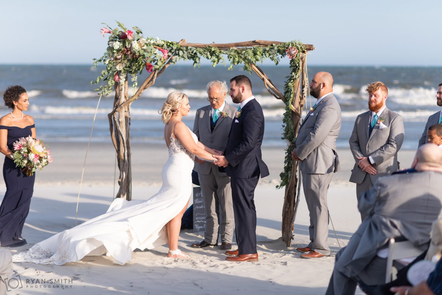 Bride holding grooms hands during a windy ceremony Grande Dunes Ocean Club
