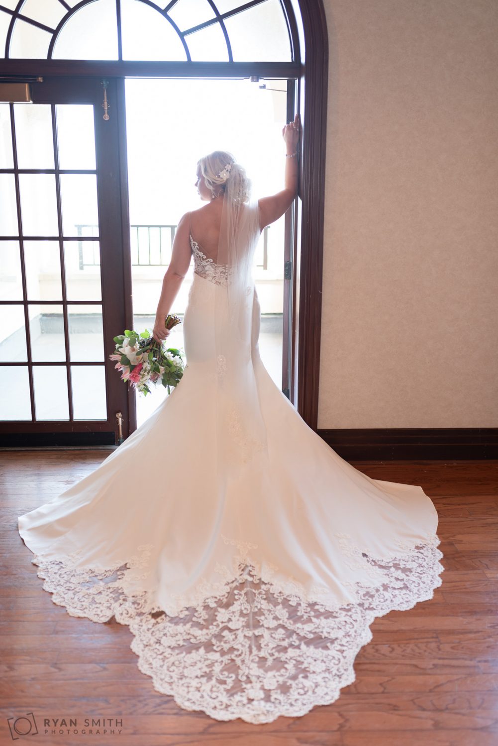 Bride standing in the doorway light with a flowing dress Grande Dunes Ocean Club