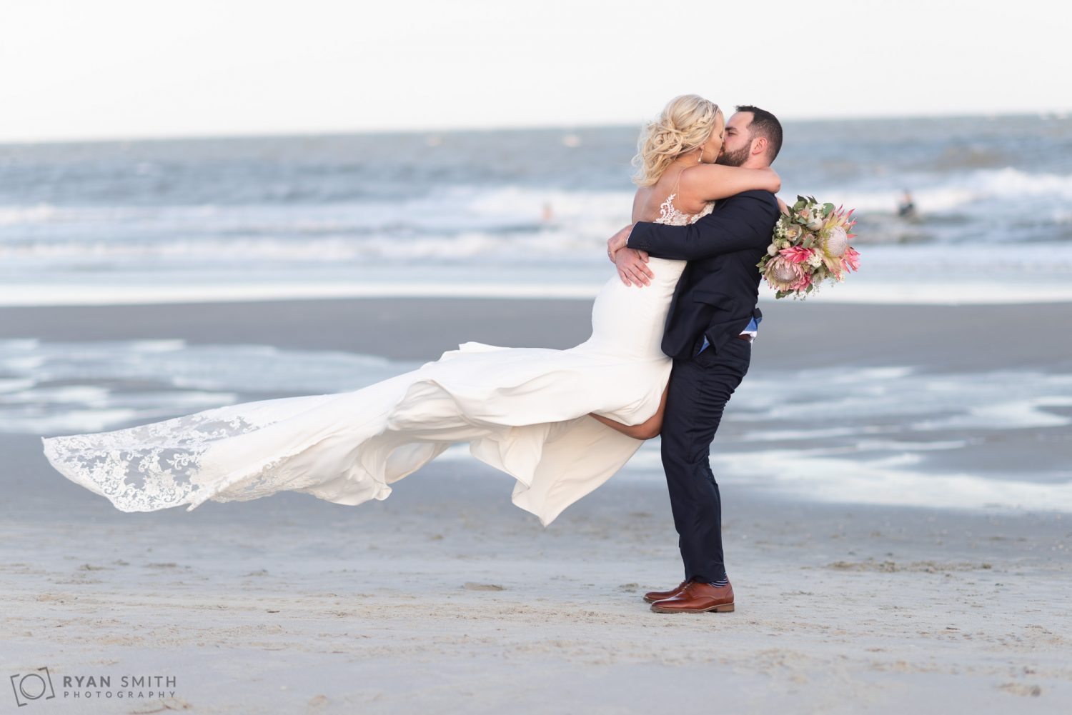 Groom lifting bride into the air for a kiss Grande Dunes Ocean Club