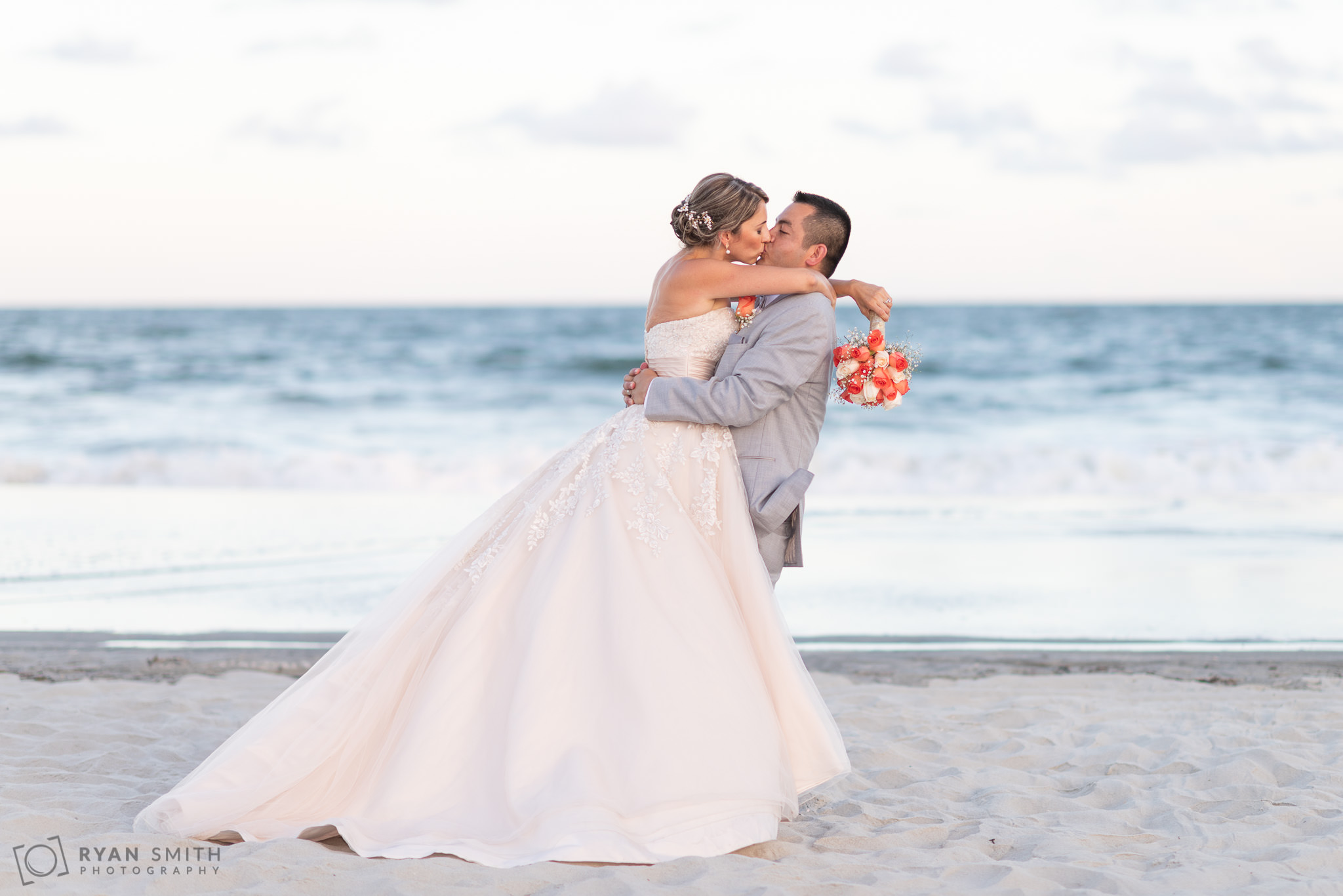 Groom lifting bride up for a kiss Grande Dunes Ocean Club