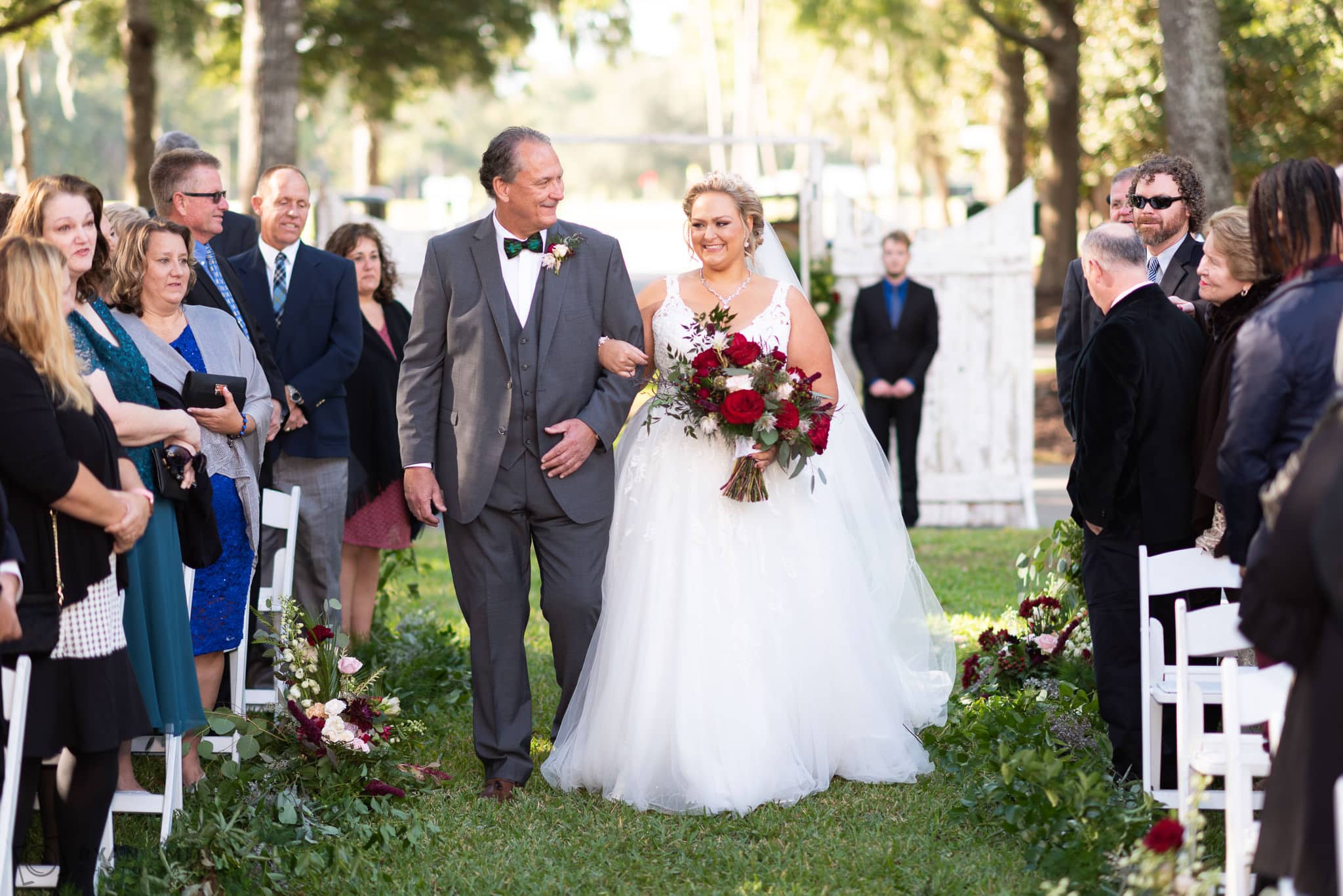 Bride and father smiling walking down the isle on the front lawn
