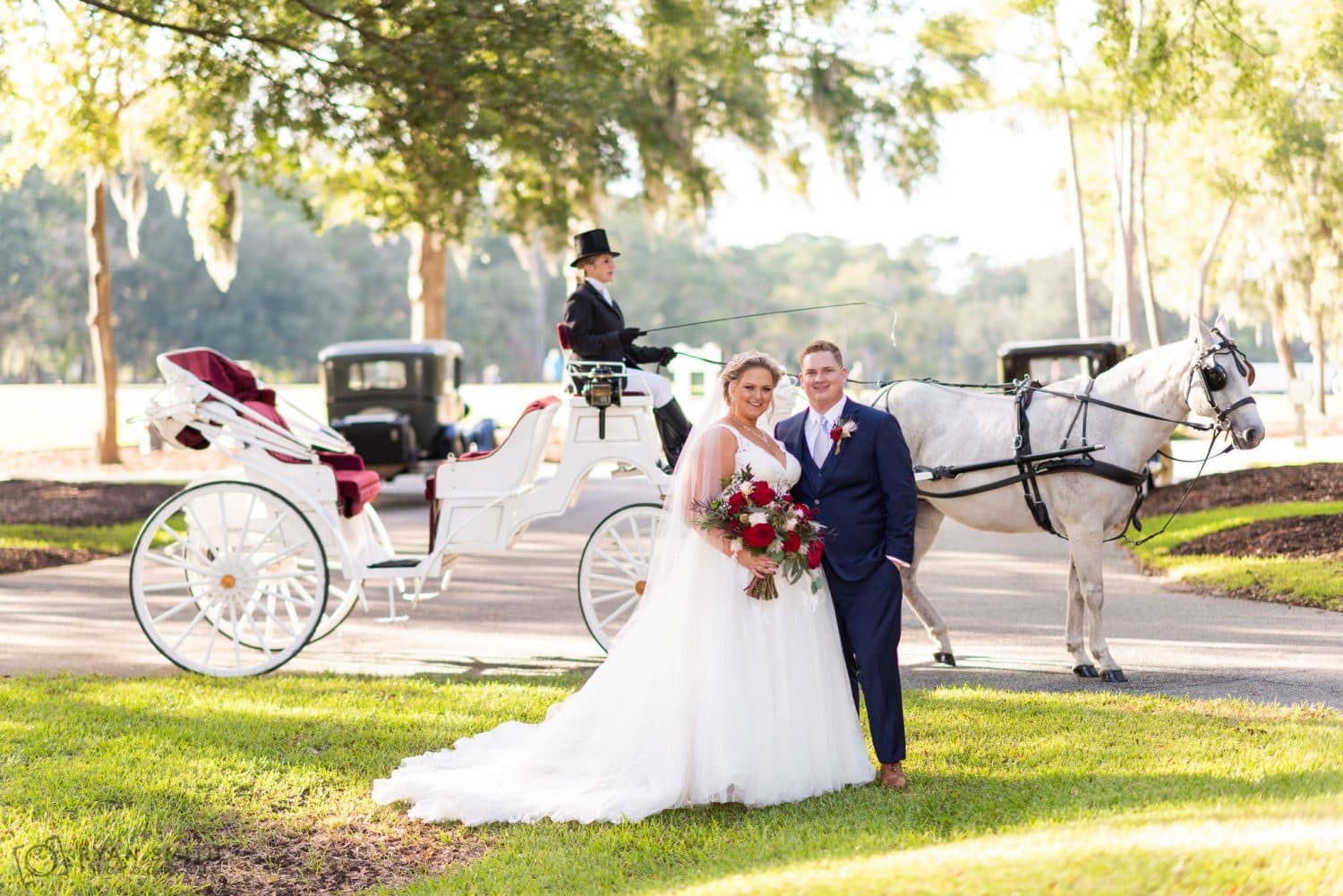 Bride and groom smiling at the camera in front of horse and carriage