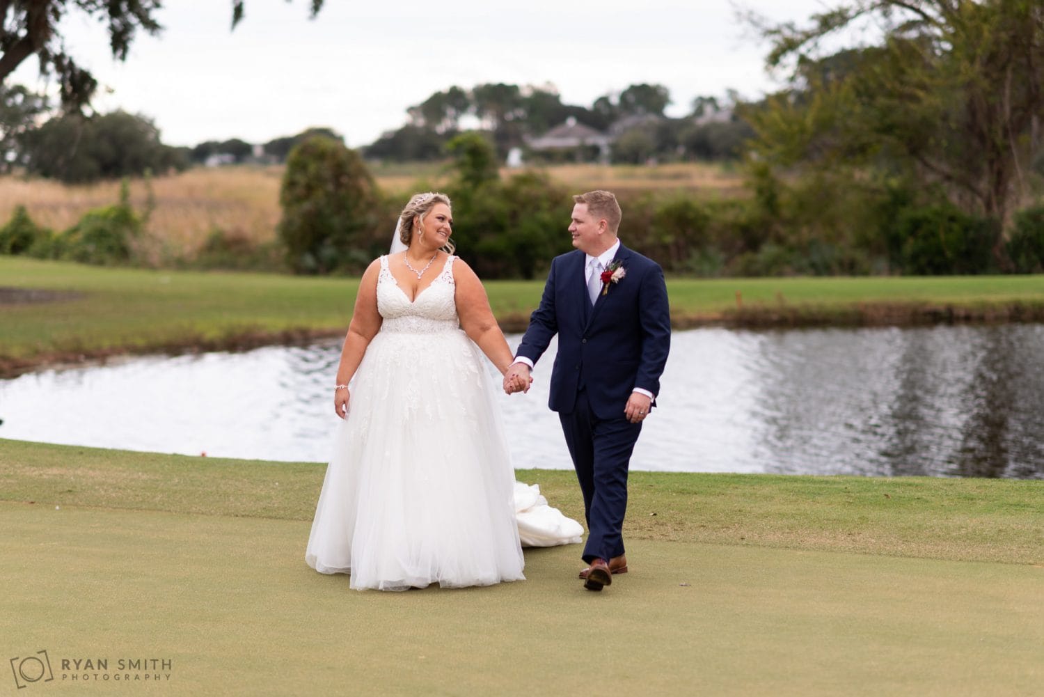 Bride and groom walking down the golf course