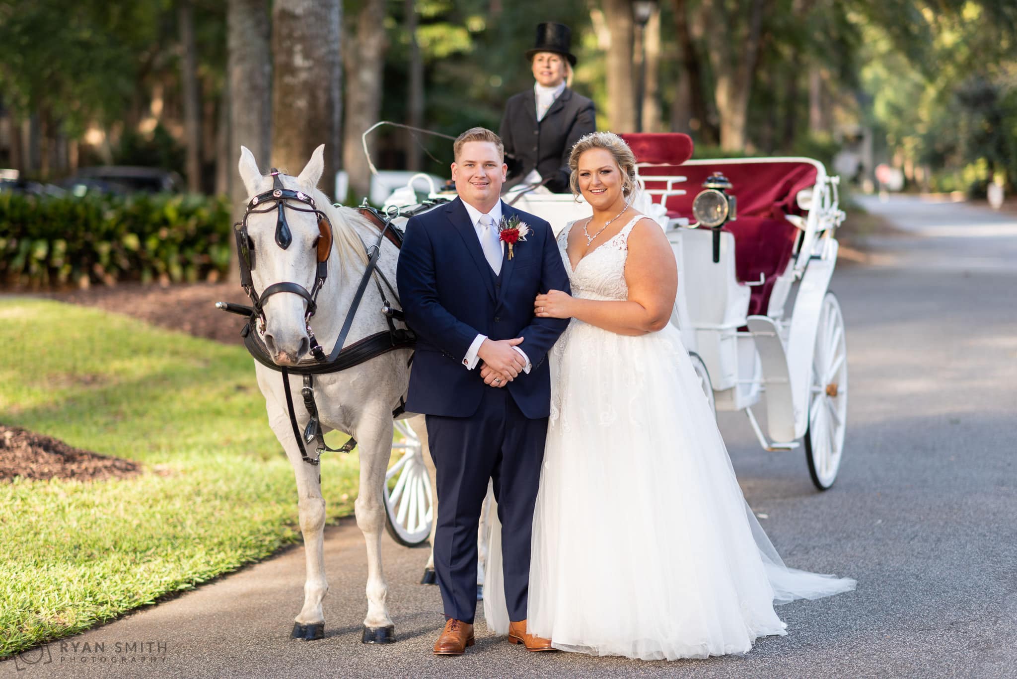 Bride holding arm of groom by the horse and carriage