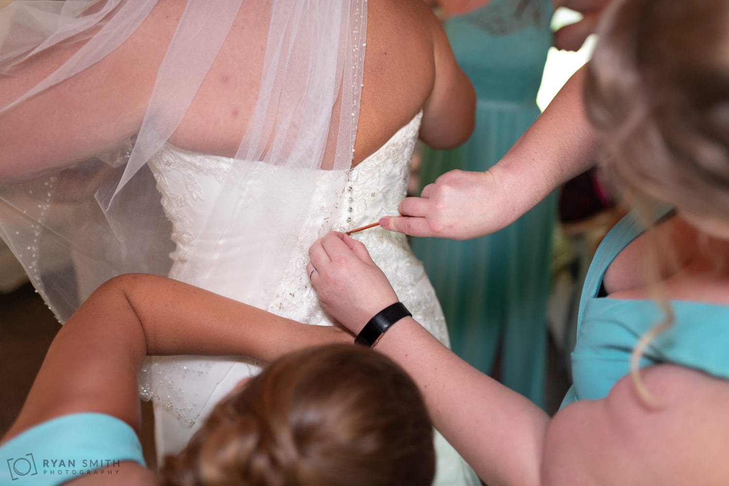 Bridesmaids helping bride hook her dress Wildberry Farm
