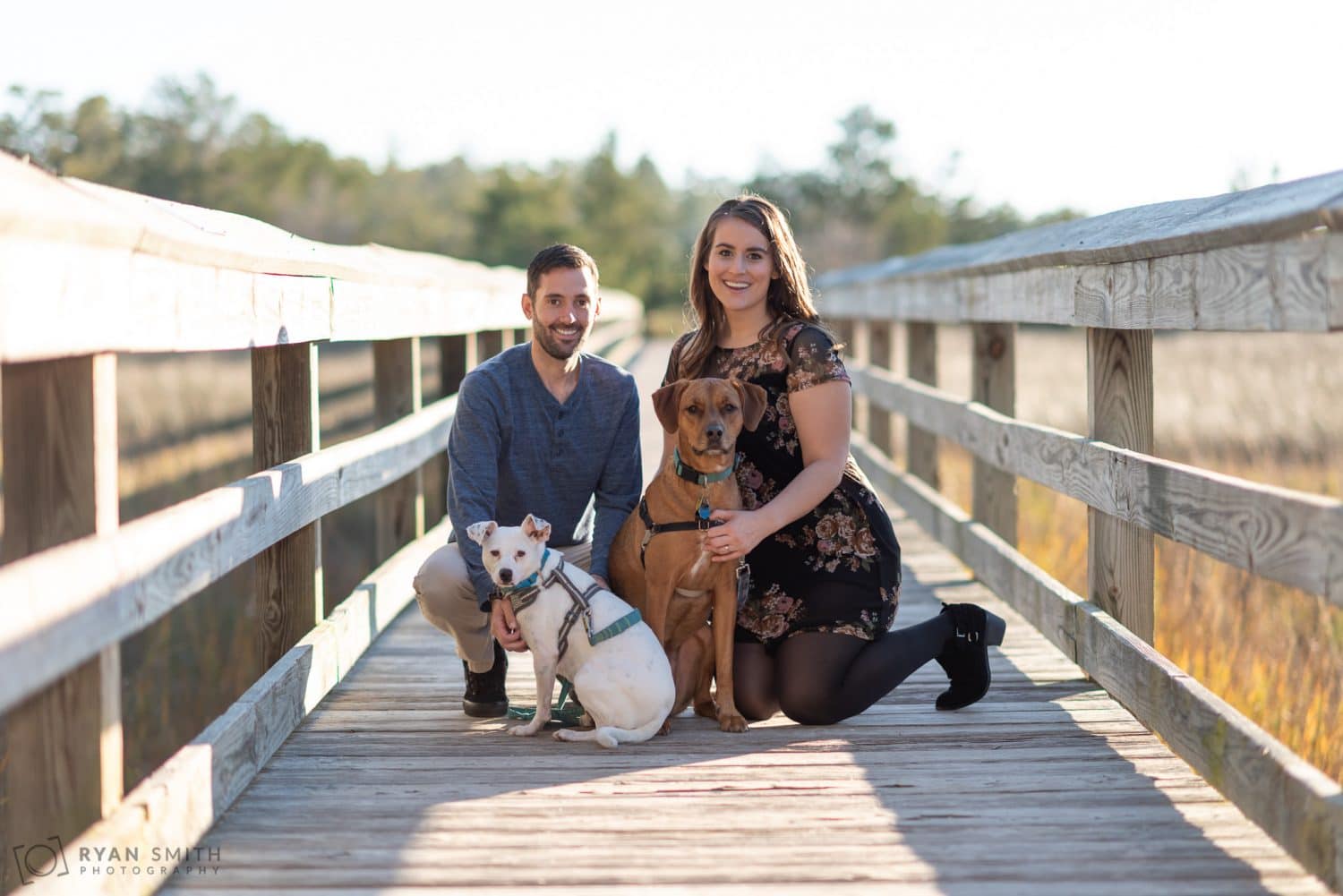 Couple crouching on the boardwalk with their dogs Vereen Memorial Gardens