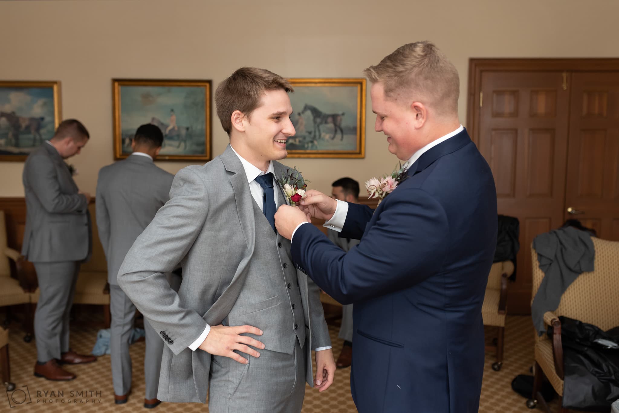 Groom helping groomsmen with his boutonniere