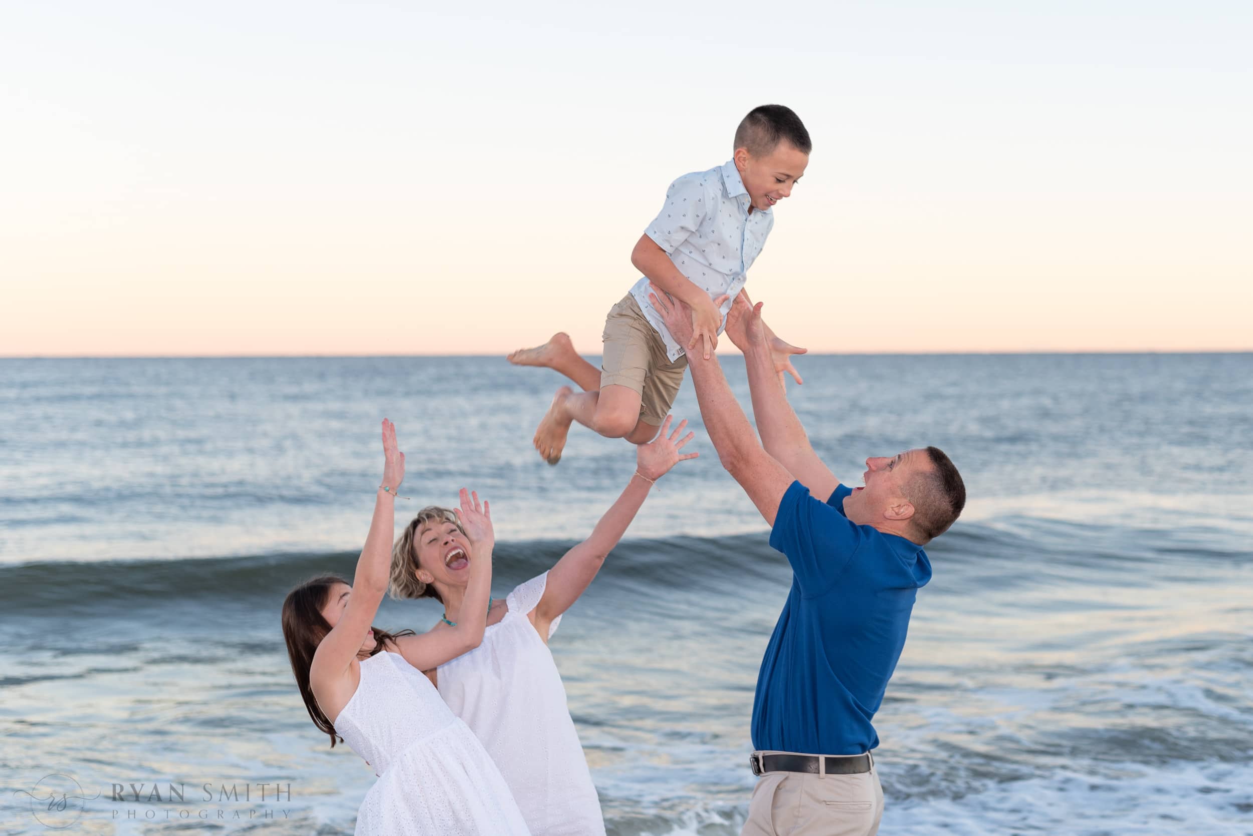 Dad throwing his big son in the air with mom and sister helping -