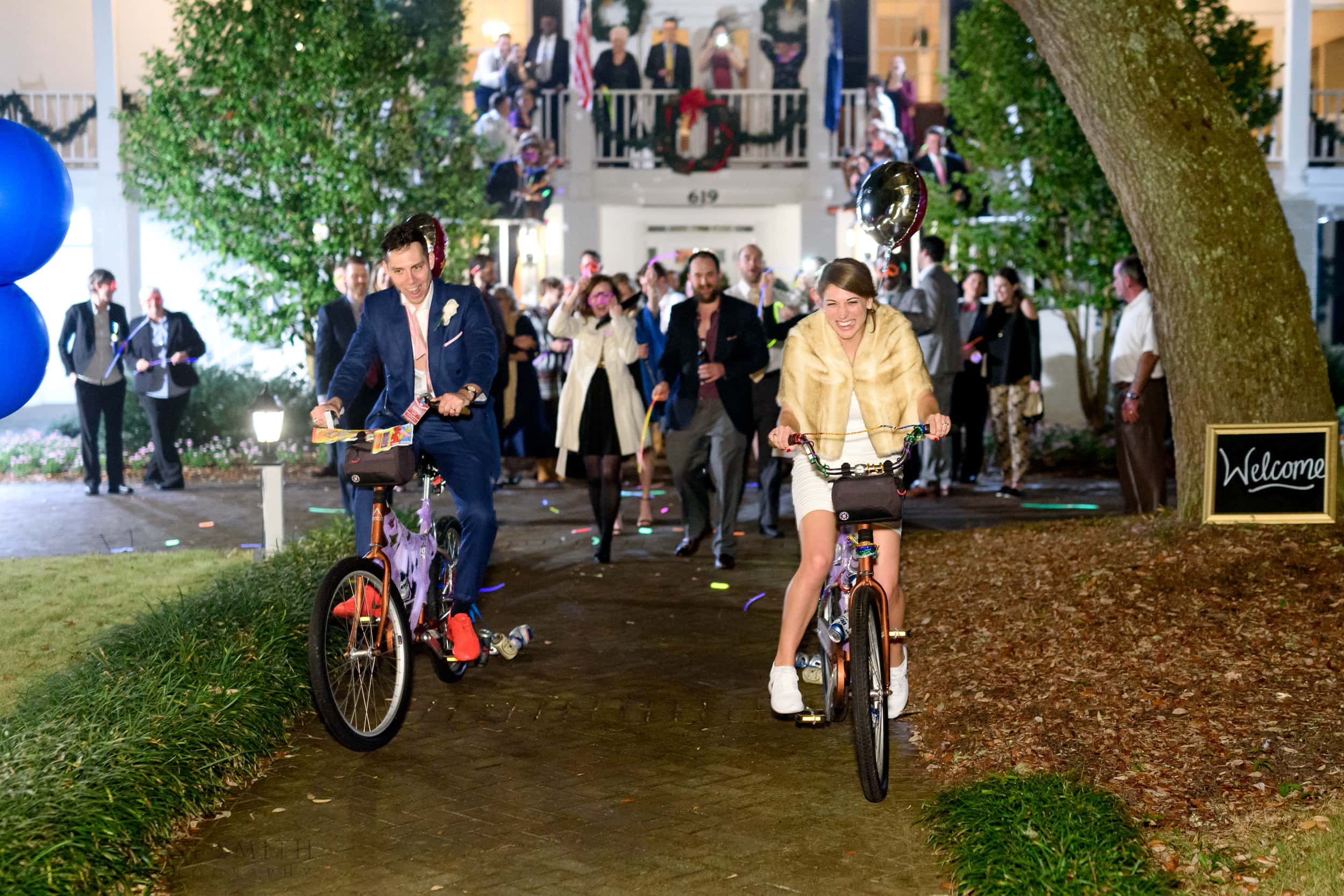 Bride and groom leaving wedding reception on bikes - Litchfield Plantation