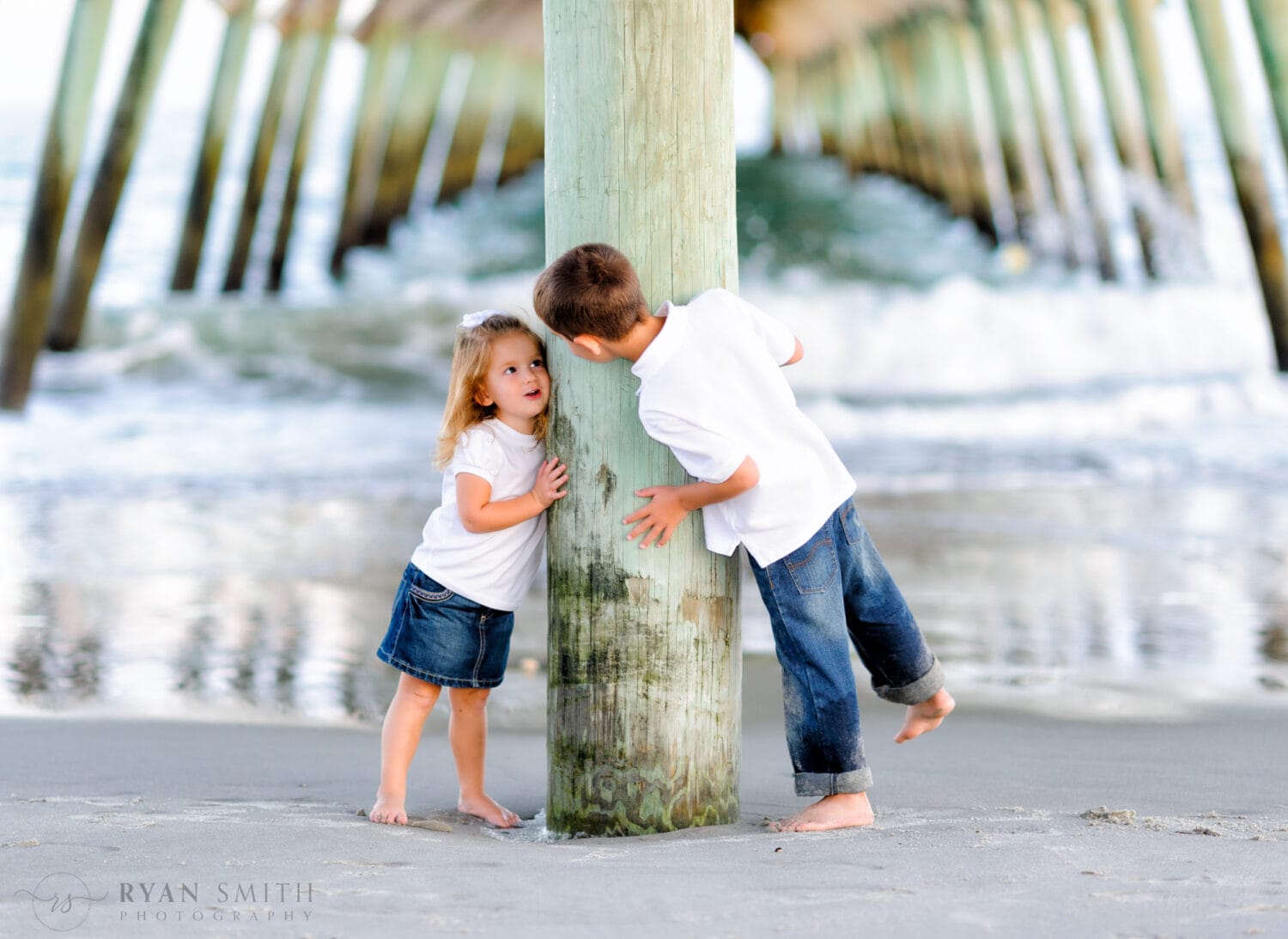 Brother and little sister having fun peeking around the pier - Myrtle Beach State Park Pier