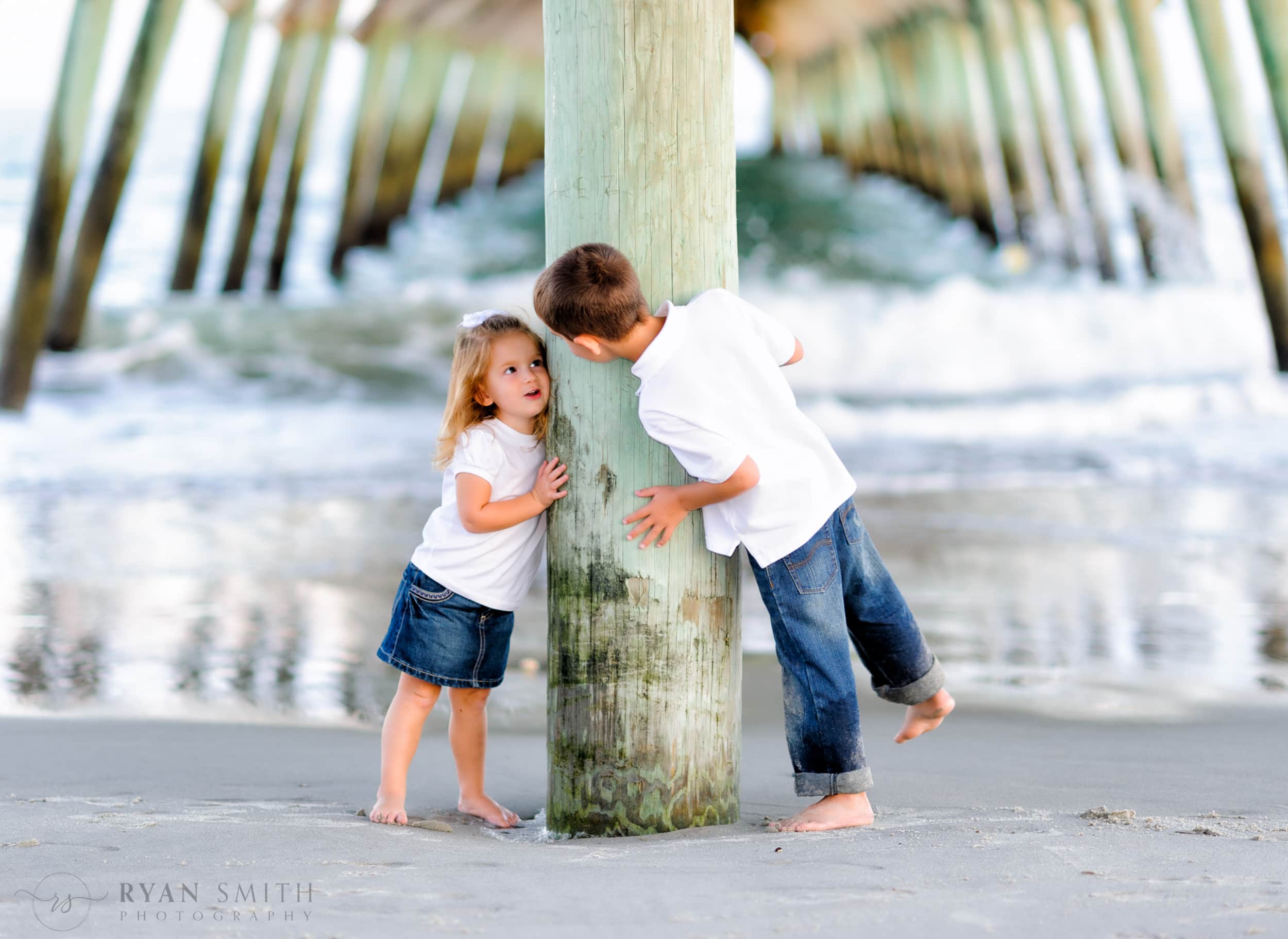 Brother and little sister having fun peeking around the pier Myrtle Beach State Park Pier