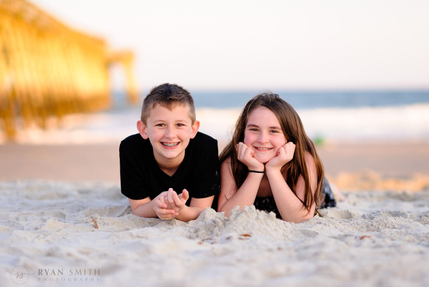 Cute brother and sister laying in the sand - Myrtle Beach