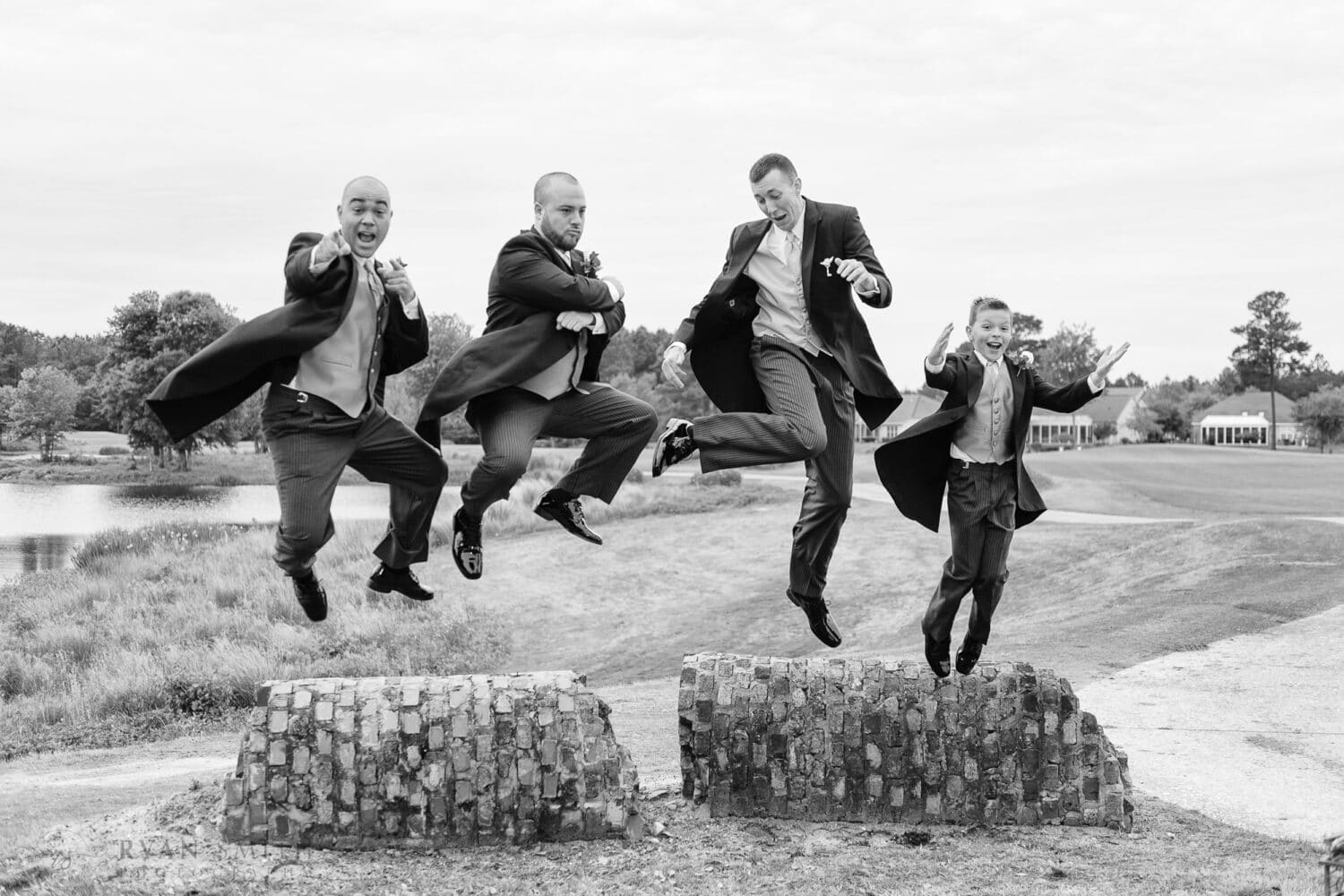 Groomsmen jumping over a fallen column on a golf course -
