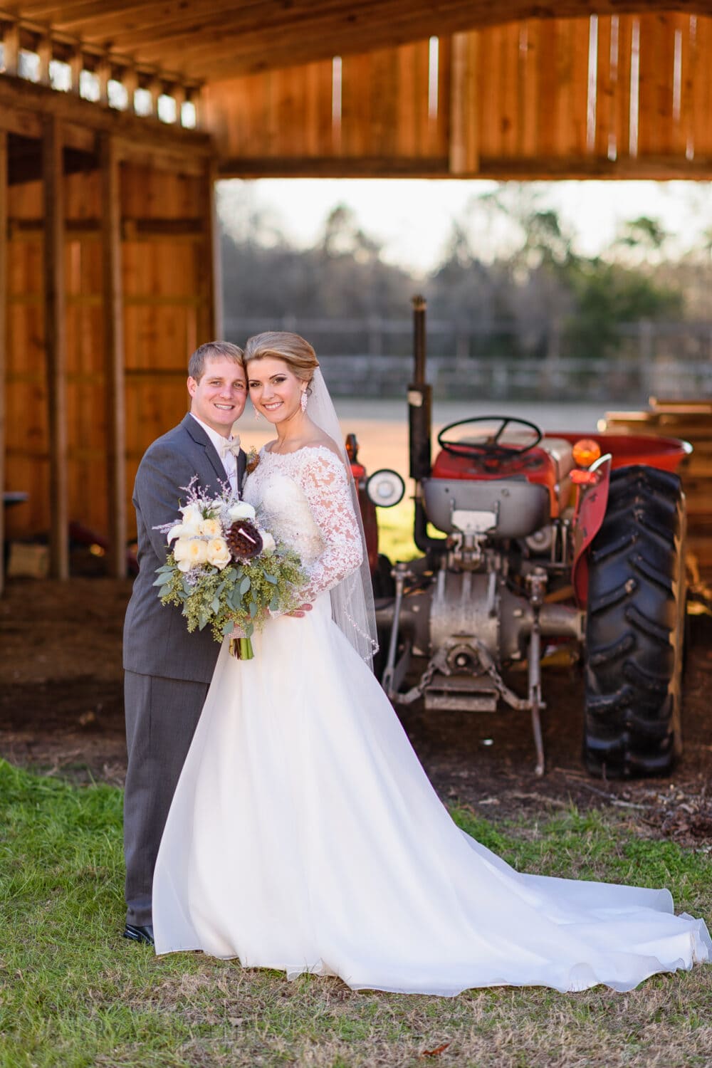 Wedding couple posing in front of barn and tractor - Wildberry Farms