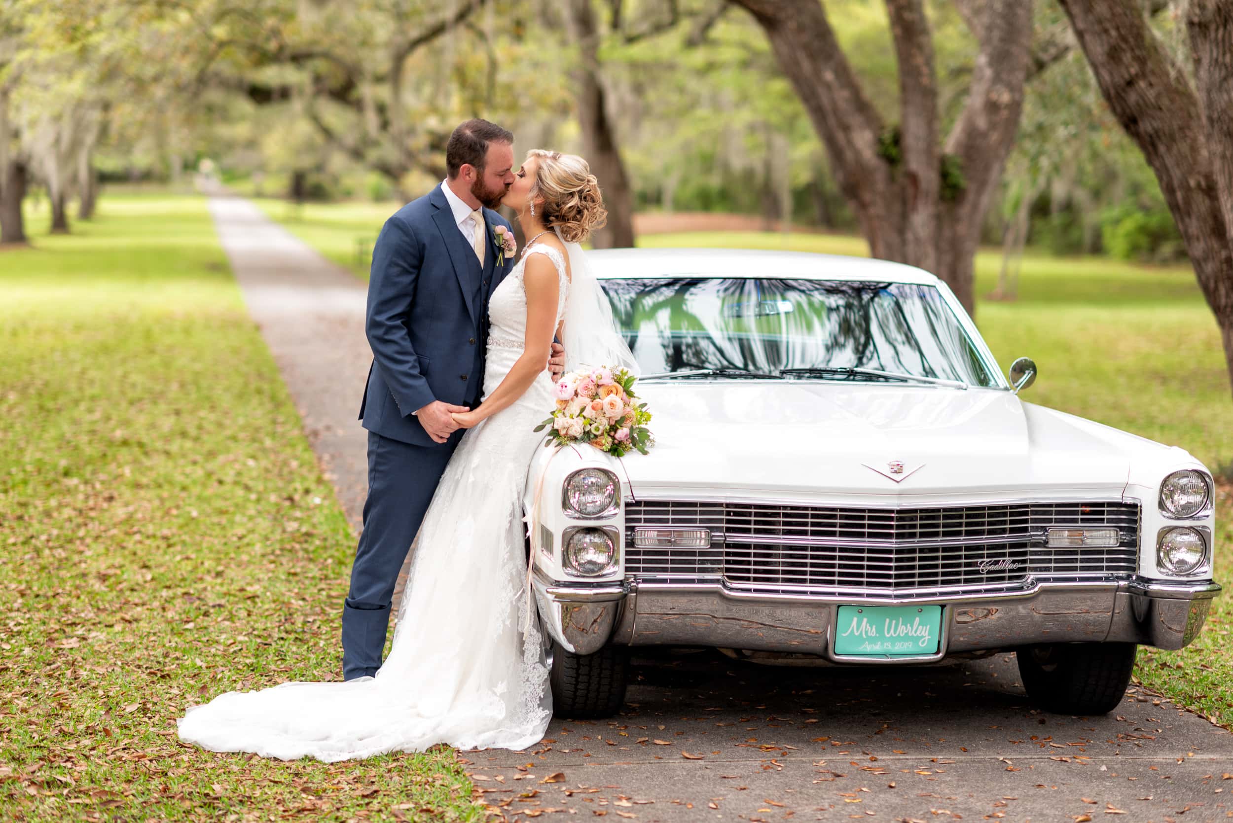 Bride and groom kissing by a classic car -