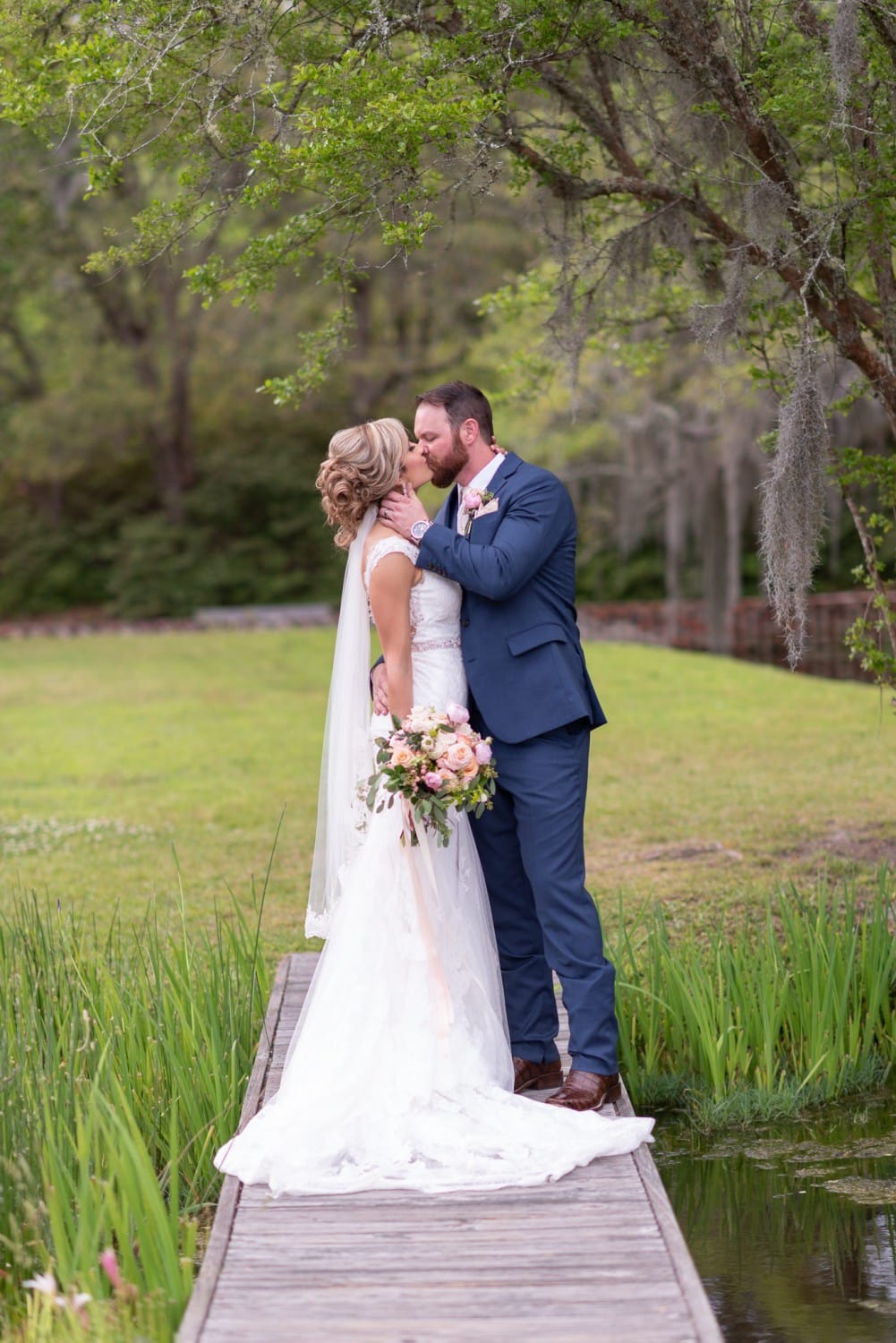 Bride and groom kissing by the lake bridge - Brookgreen Gardens