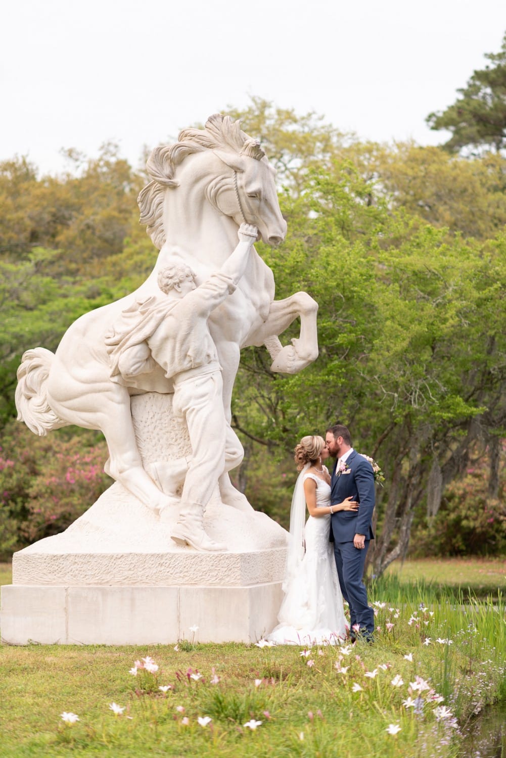 Bride and groom kissing under the Youth Taming the Wild Statue - Brookgreen Gardens