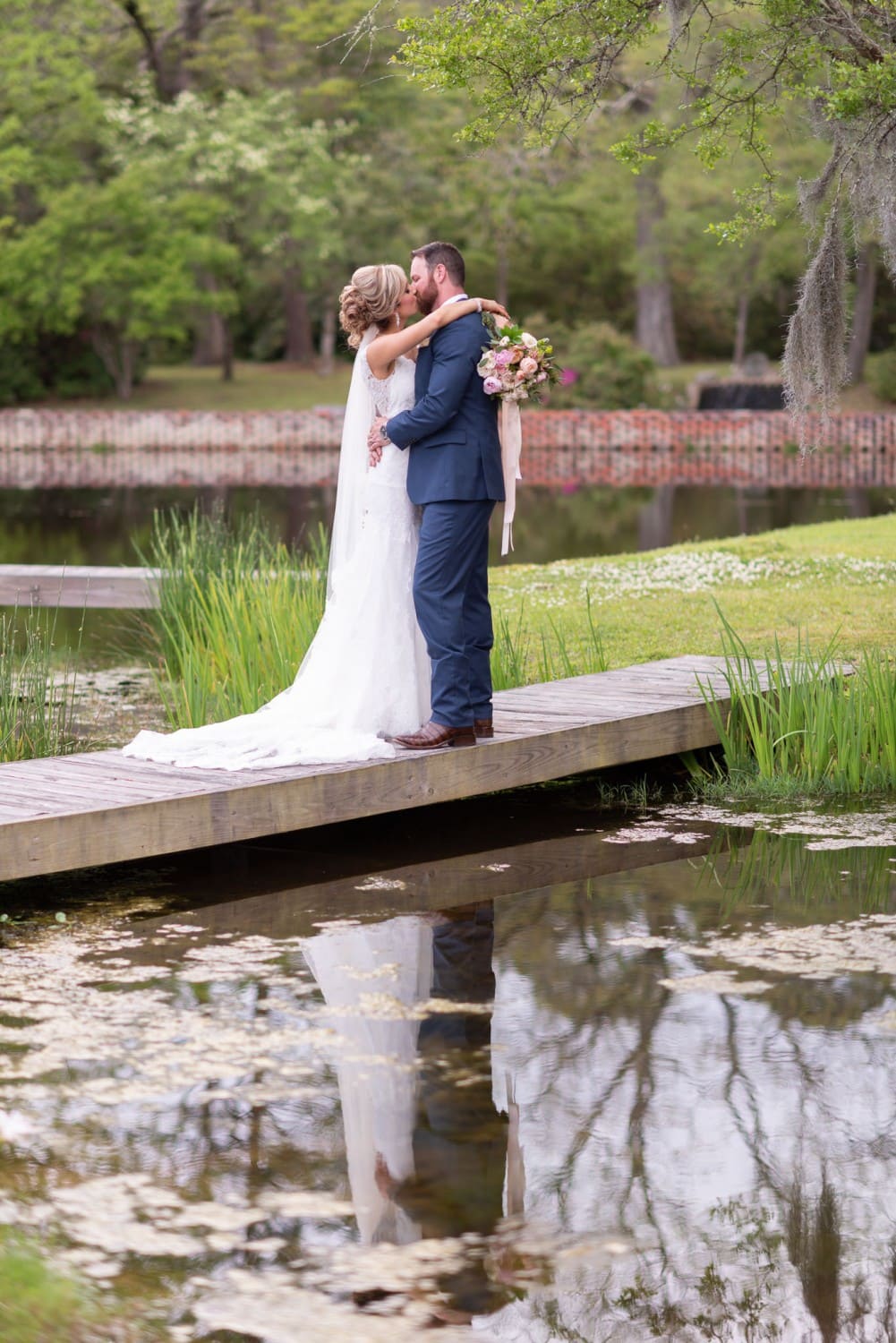 Bride and groom reflecting in the pond by the statue - Brookgreen Gardens