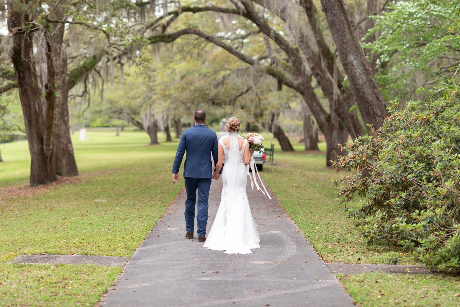 Bride and groom walking towards the classic car - Brookgreen Gardens