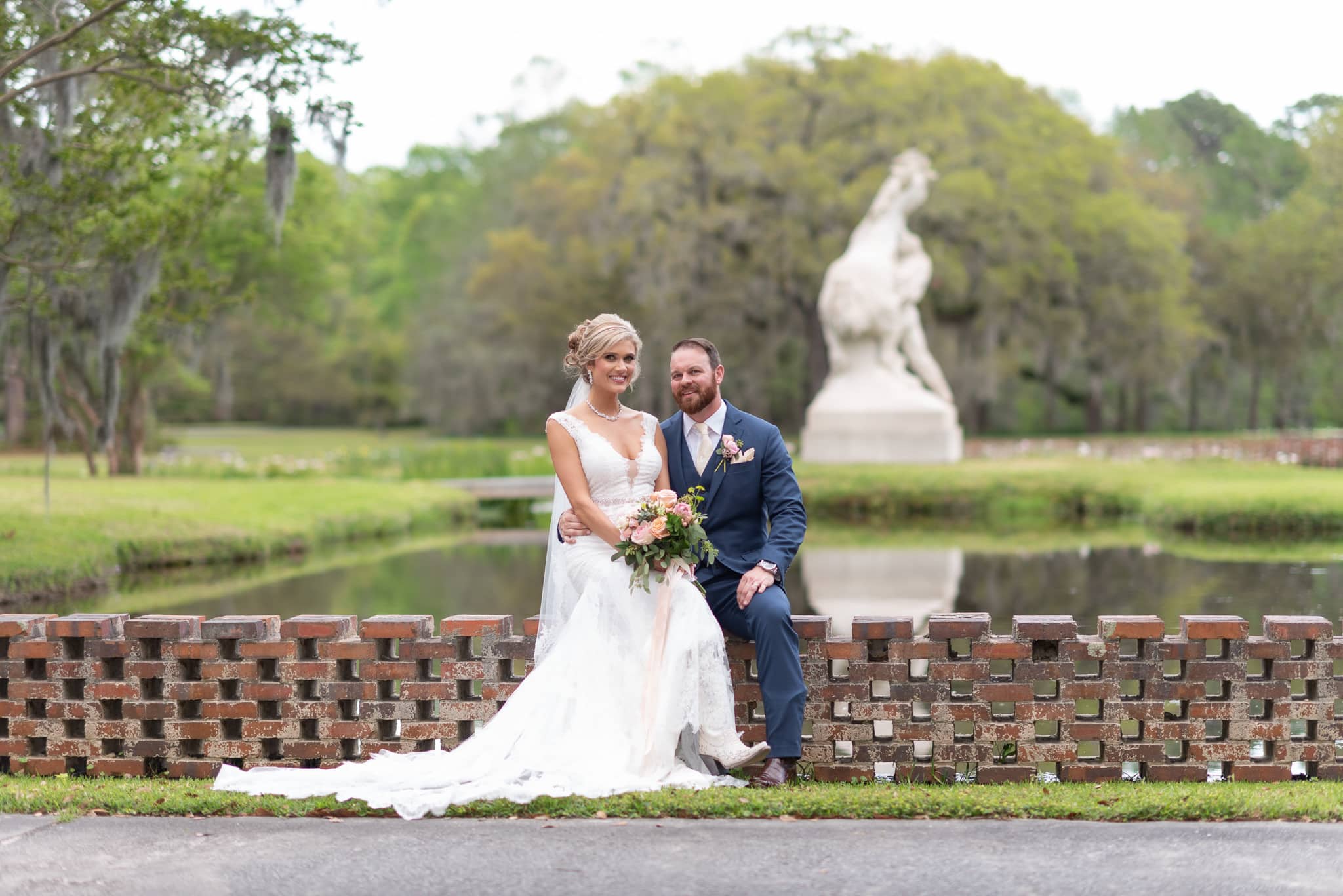 Bride and groom with "Youth Taming the Wild" sculpture in the background - Brookgreen Gardens