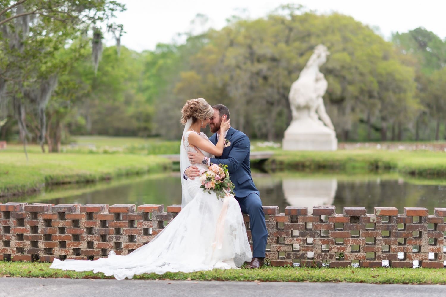Bride and groom with "Youth Taming the Wild" sculpture in the background - Brookgreen Gardens