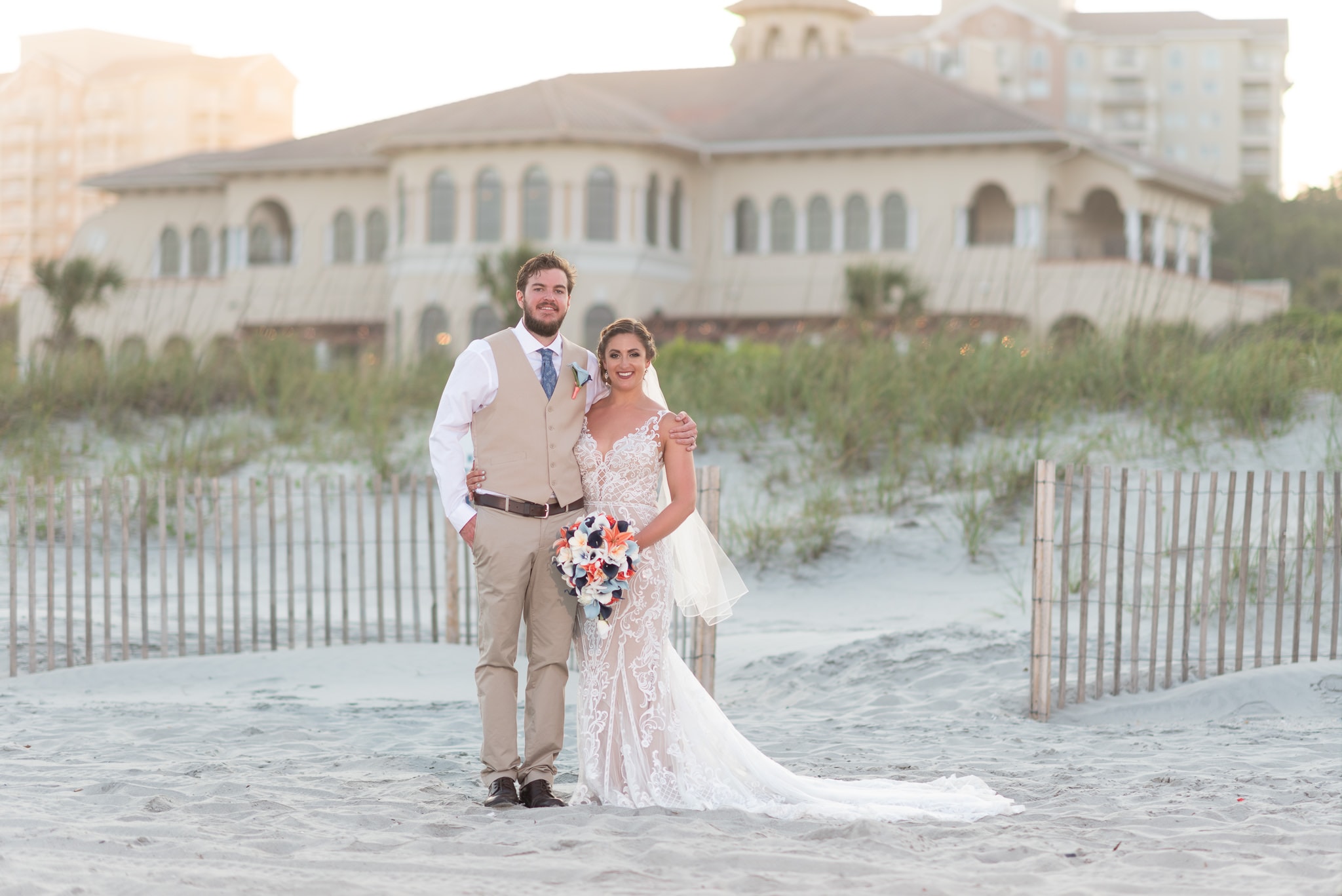 Bride and groom with the clubhouse in the background Grande Dunes Ocean Club - Myrtle Beach