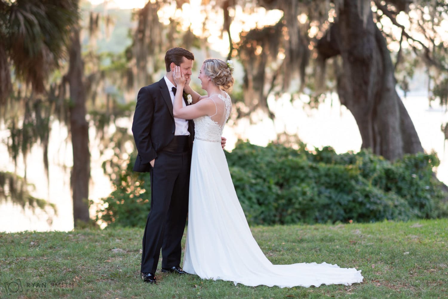 Bride pulling groom in for a kiss with her hands on his cheeks  Wachesaw Plantation