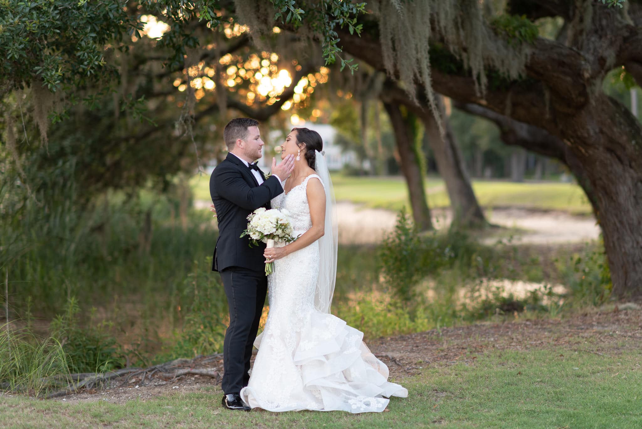 Groom touching brides face backlit by the sunset Pawleys Plantation
