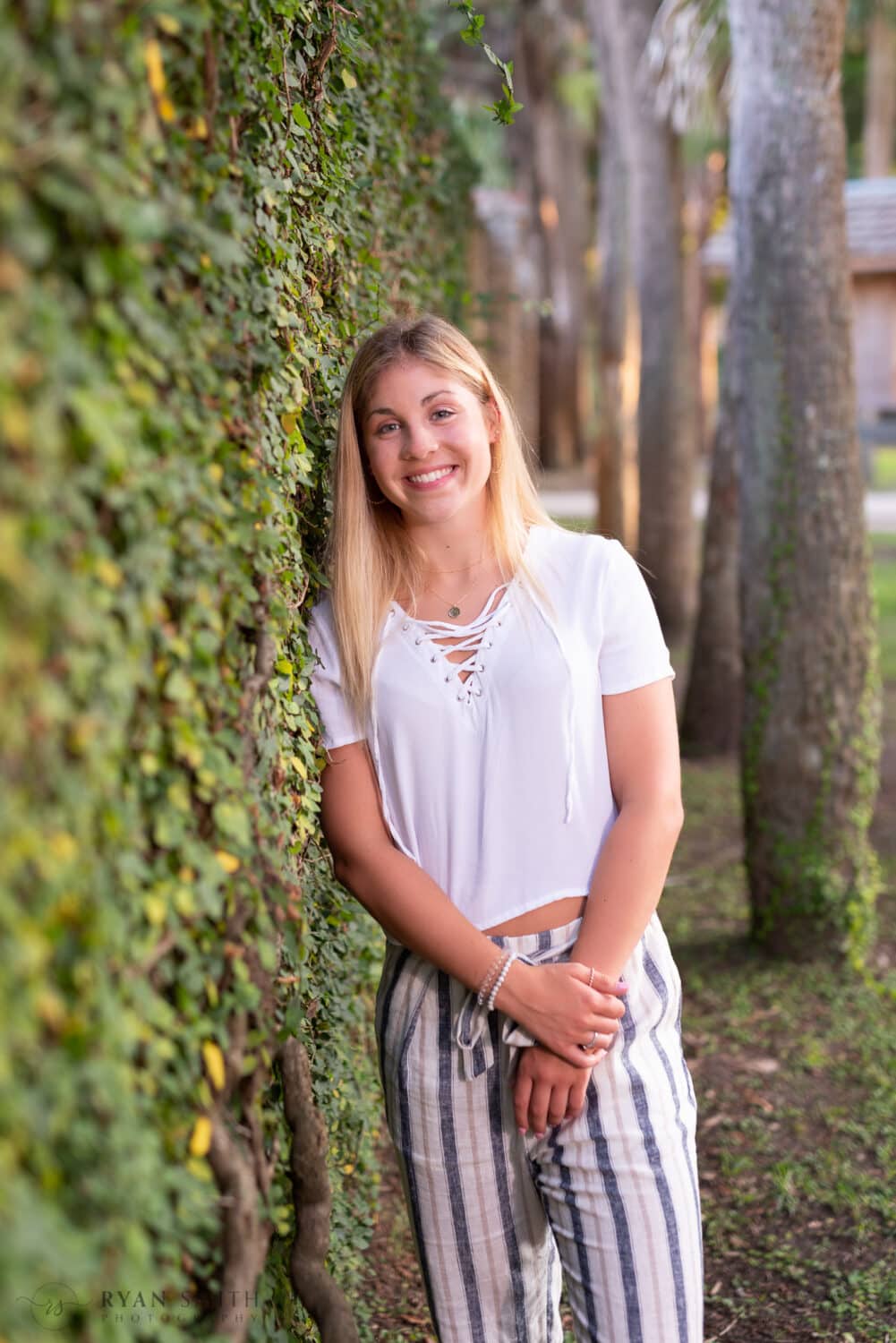 Girl senior portrait leaning against the ivy wall of the Atalaya Castle - Huntington Beach State Park