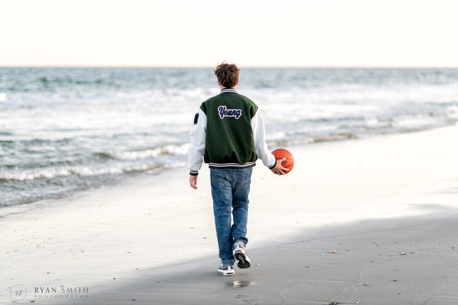 Young man walking down the beach holding basketball - Myrtle Beach State Park