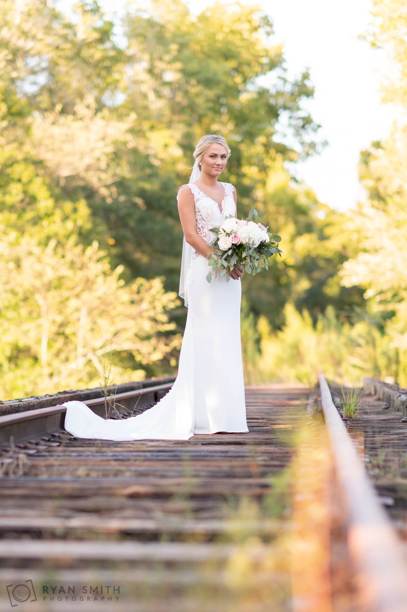 Bride on train tracks holding bouqeut - Conway River Walk