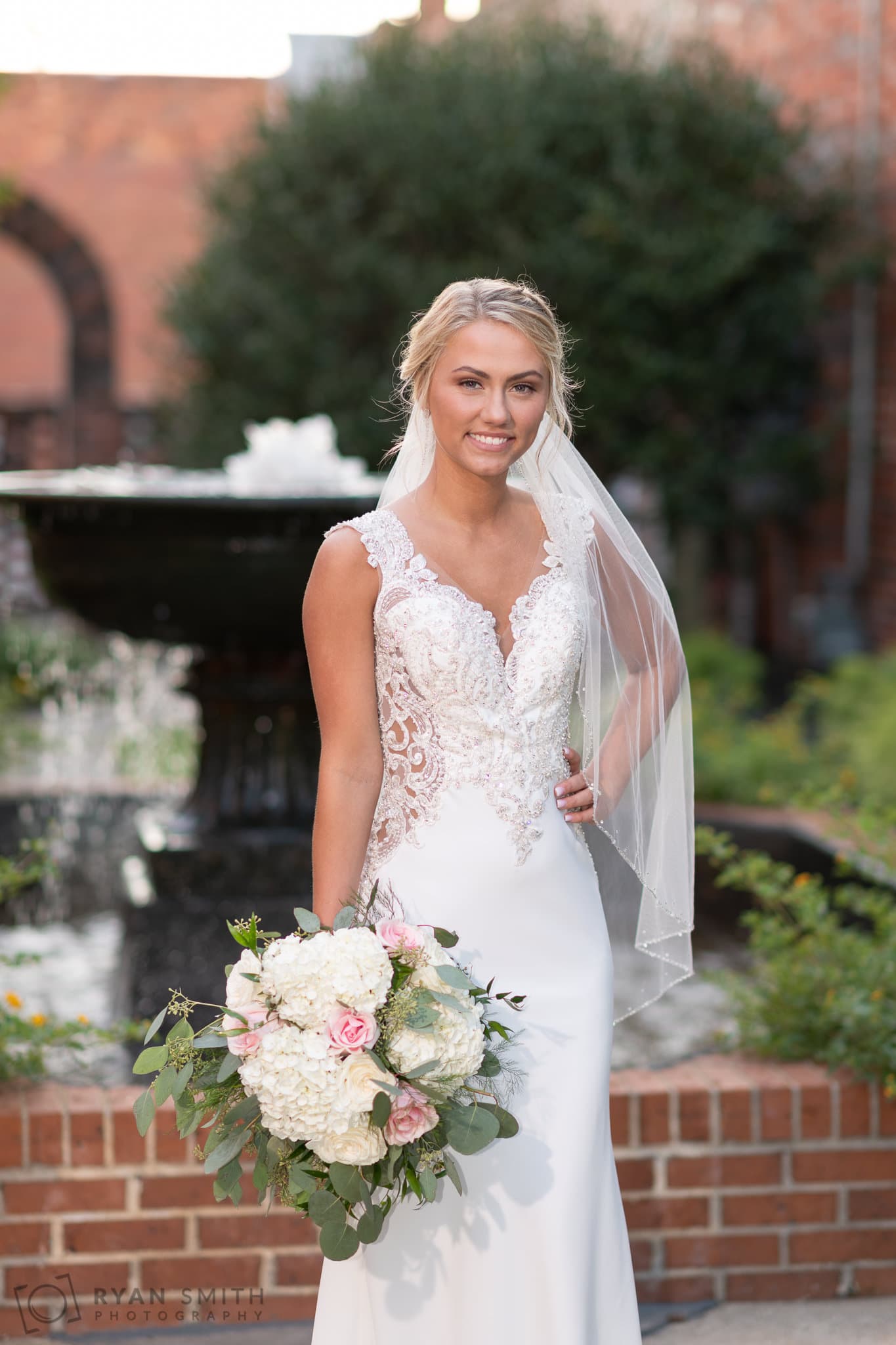 Bride standing in front of the courthouse fountain - Conway River Walk